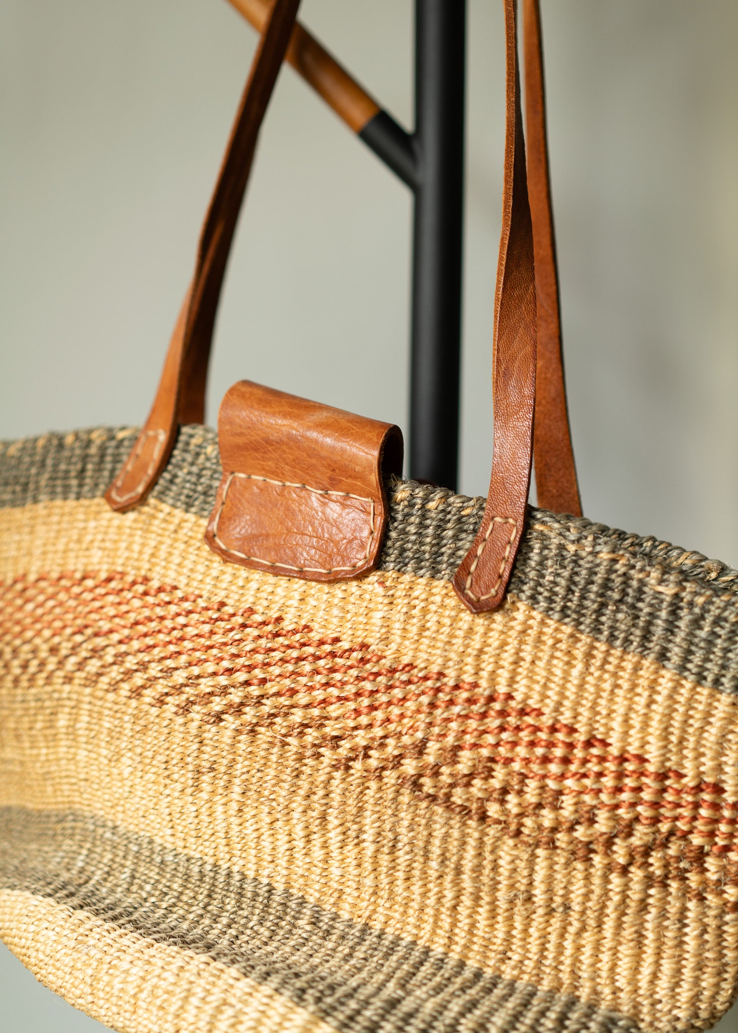 Woven bag with leather strap and pocket on a neutral background