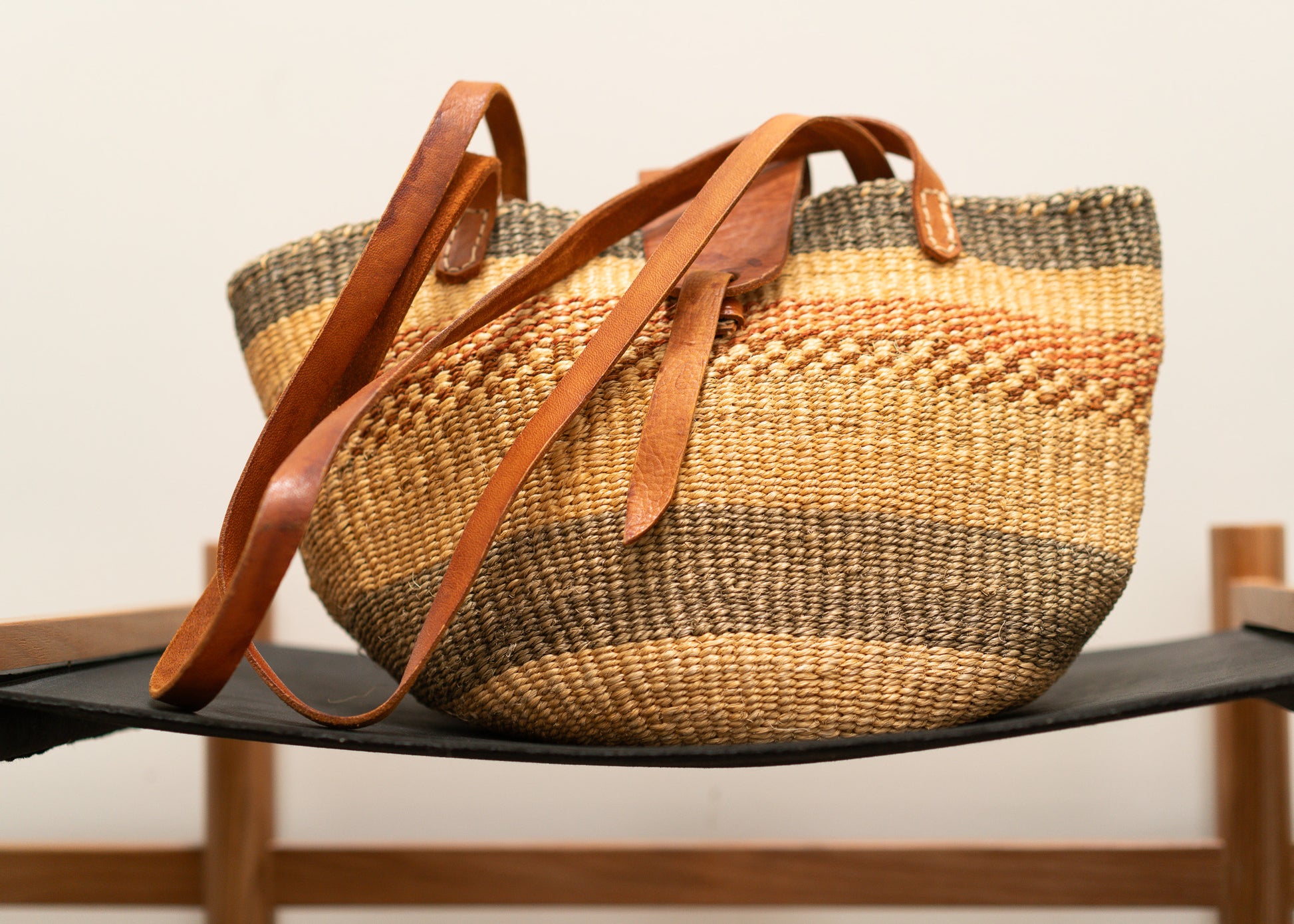 vintage woven basket with leather handles on a black surface