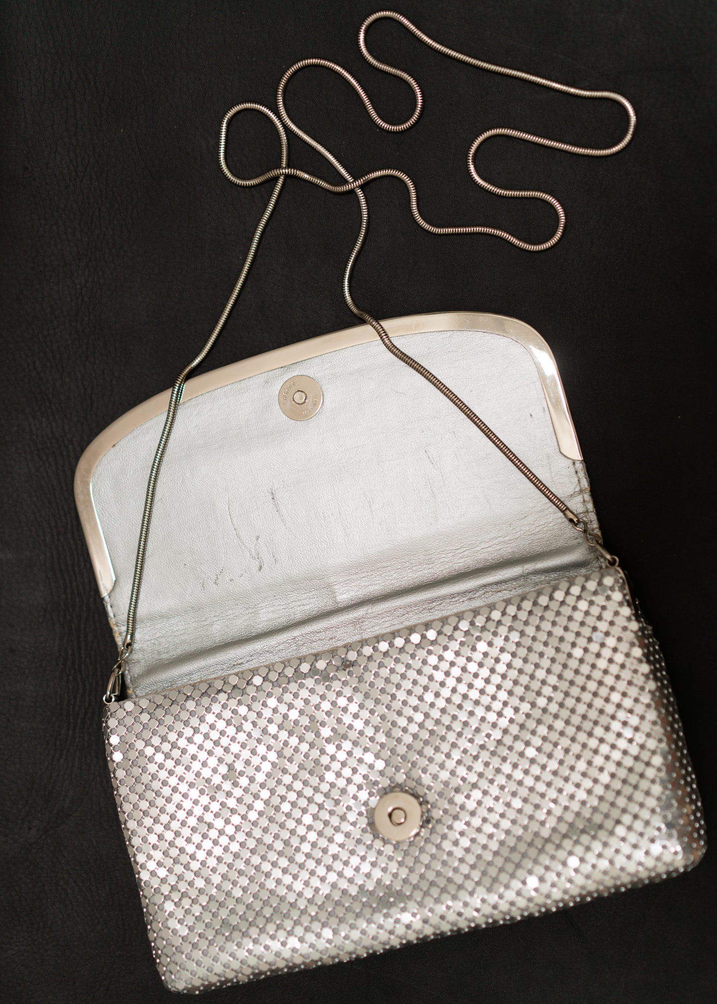 Silver mesh handbag with a chain strap on a black background