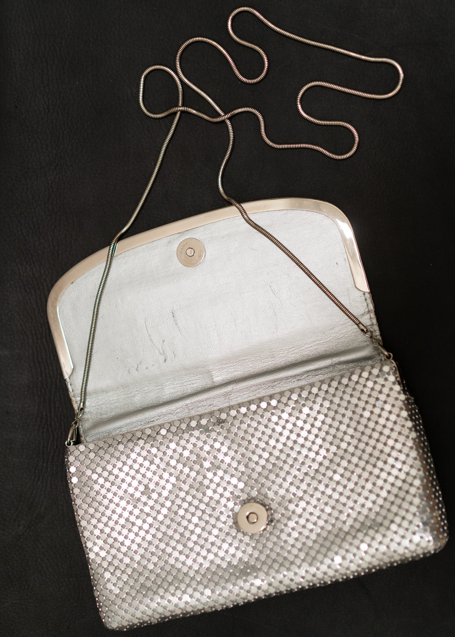 Silver mesh handbag with a chain strap on a black background