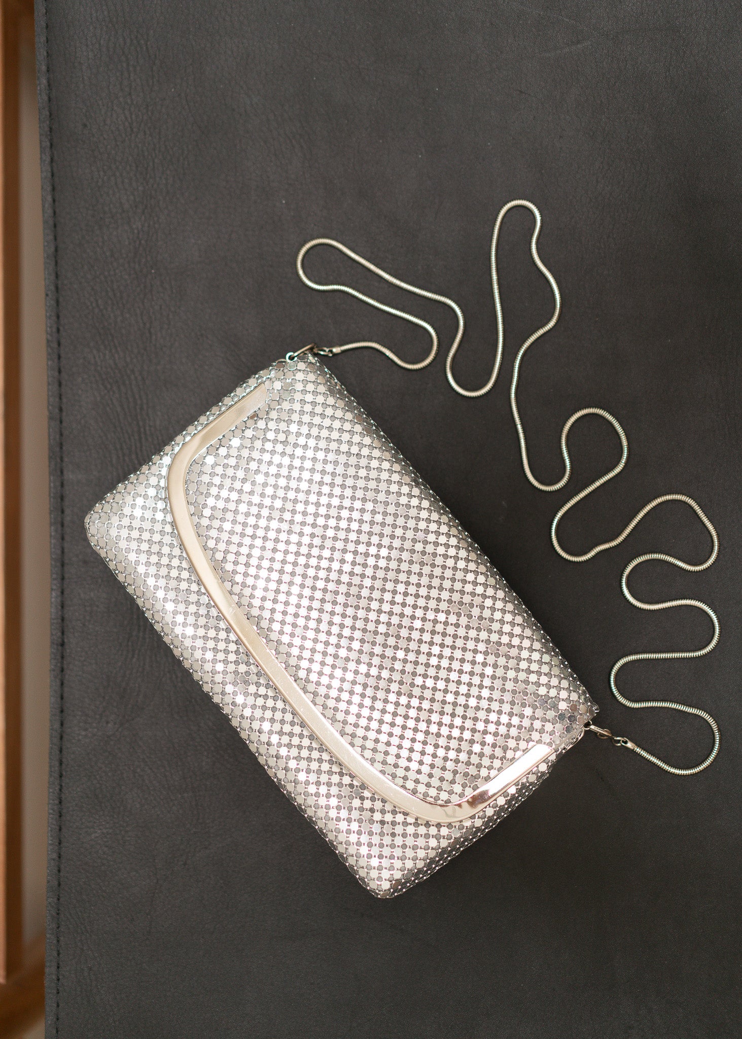 Silver mesh handbag with a chain strap on a dark surface