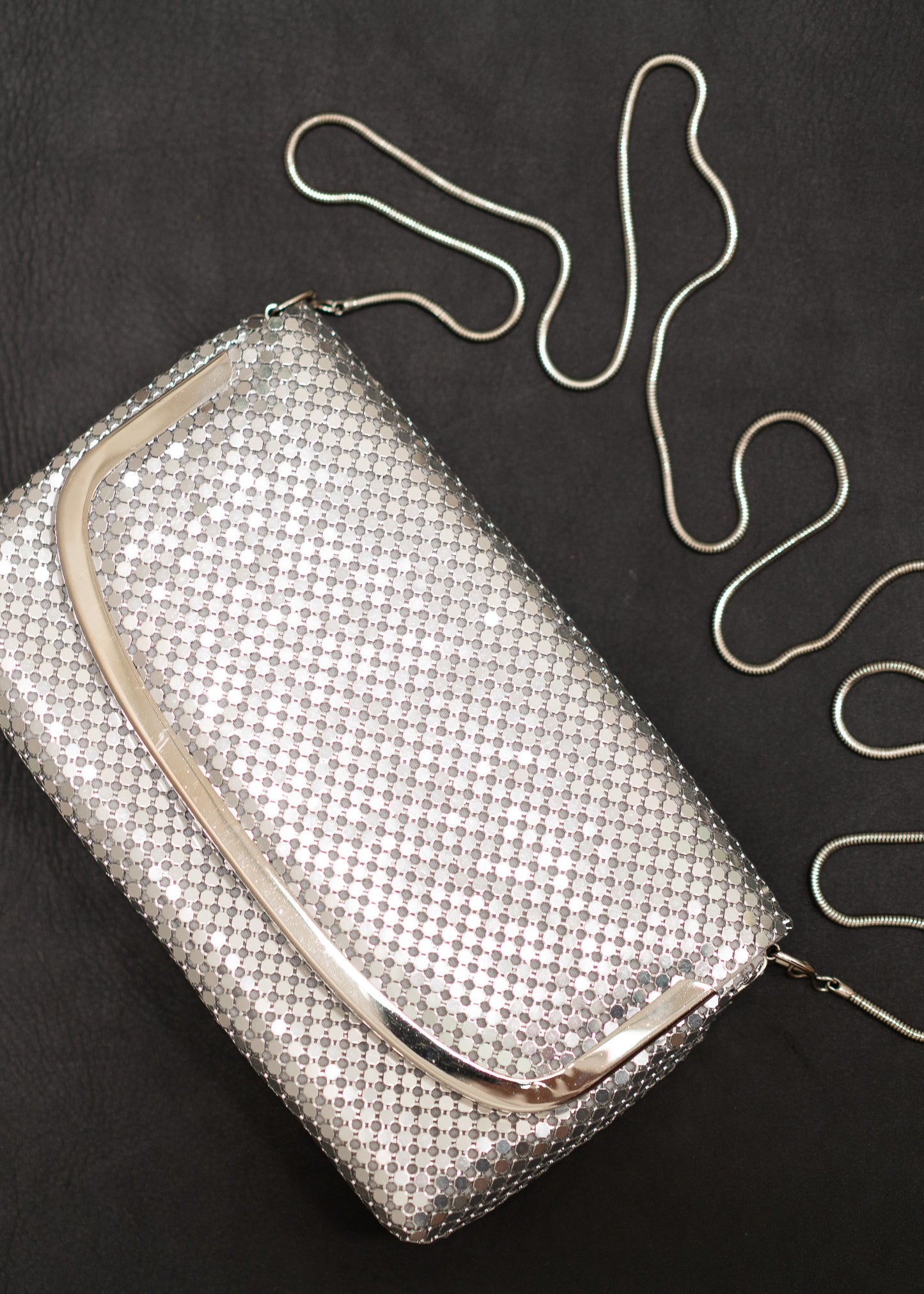 Silver mesh handbag with a chain strap on a black background