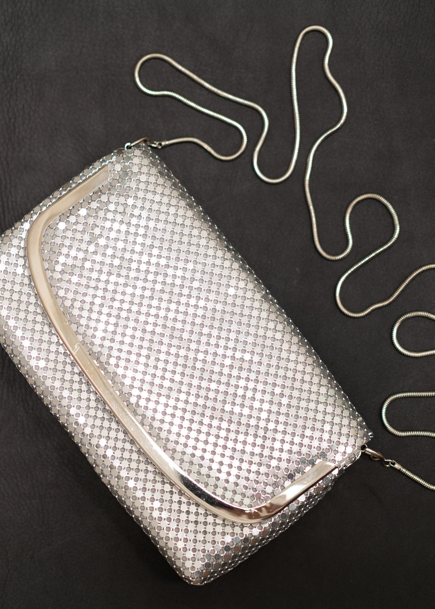 Silver mesh handbag with a chain strap on a black background