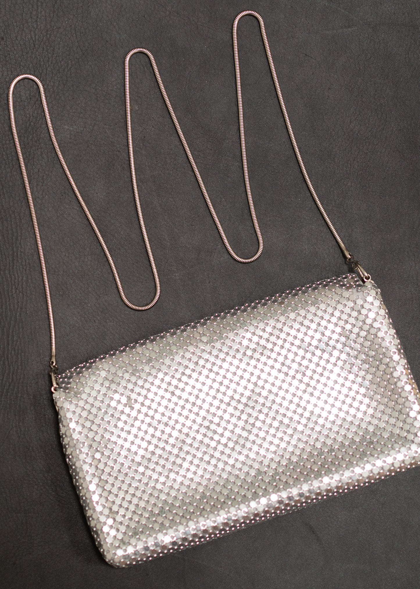 Silver mesh handbag with a long strap on a dark background