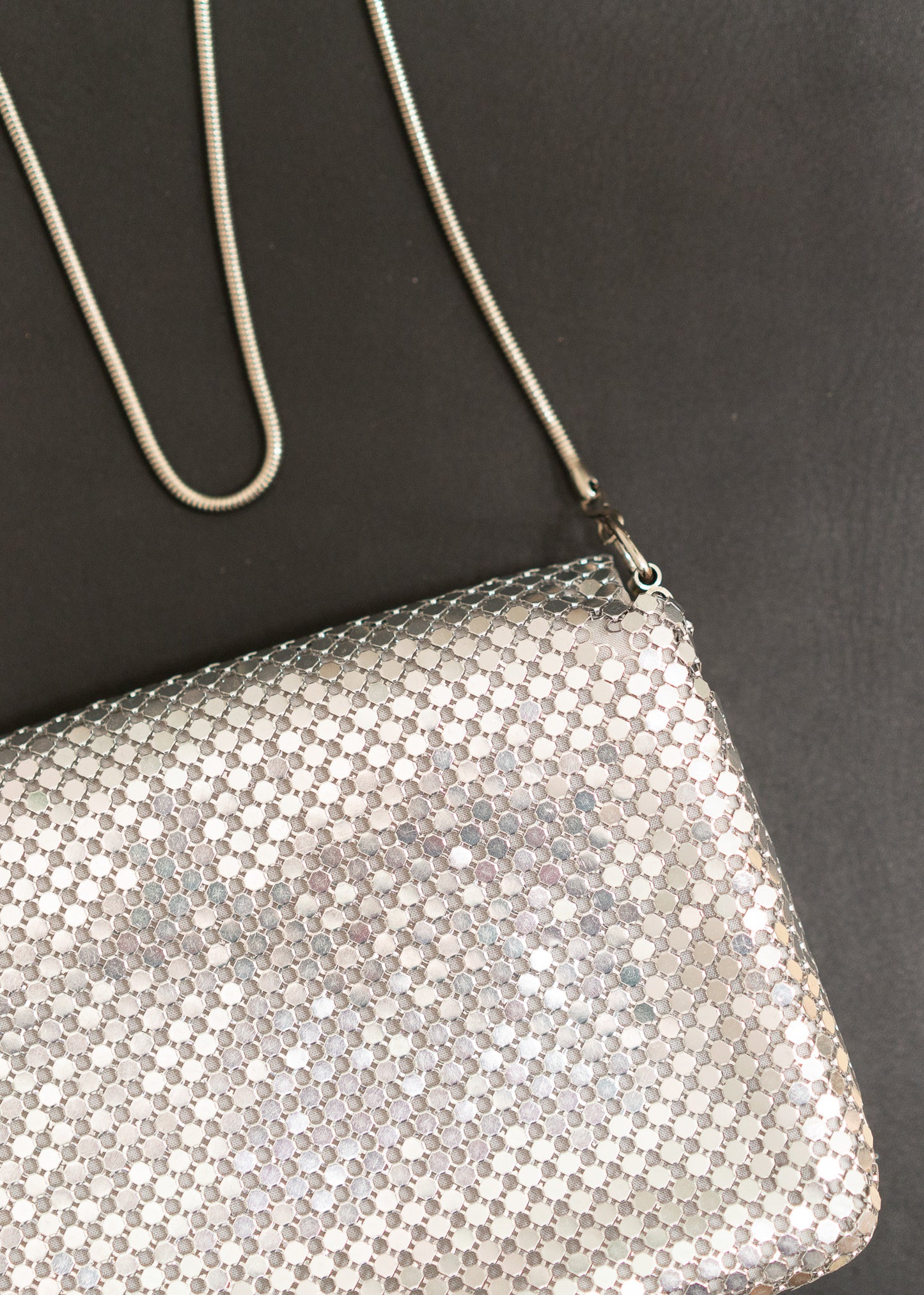 silver metal mesh handbag with chain strap on a black background