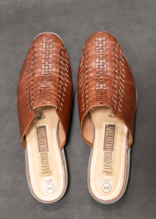 Pair of brown woven sandals on a gray background