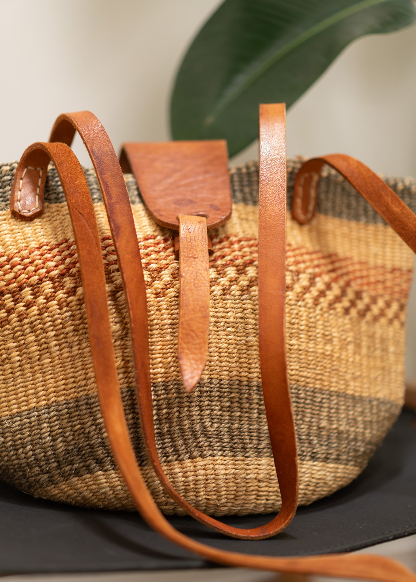 vintage woven bag with leather straps on a neutral background