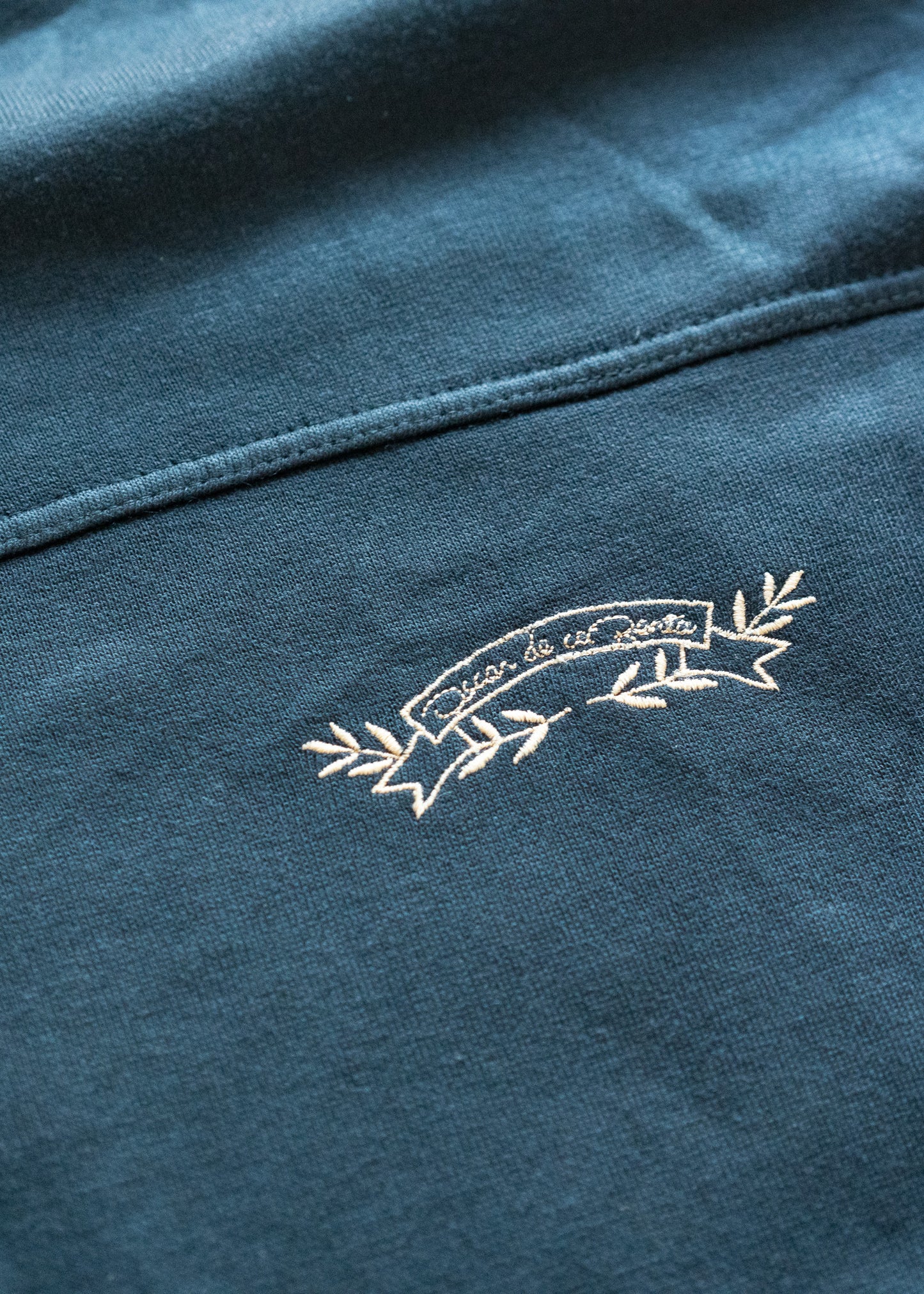 Close-up of a blue fabric with an embroidered white logo on a dark background