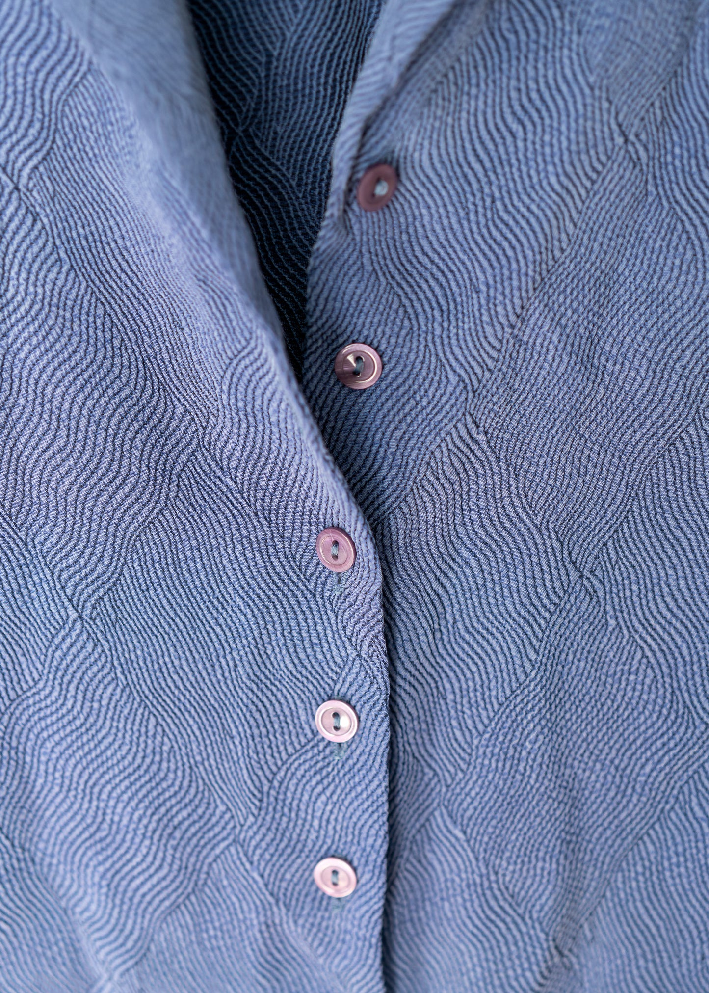 Close-up of a blue textured shirt with buttons