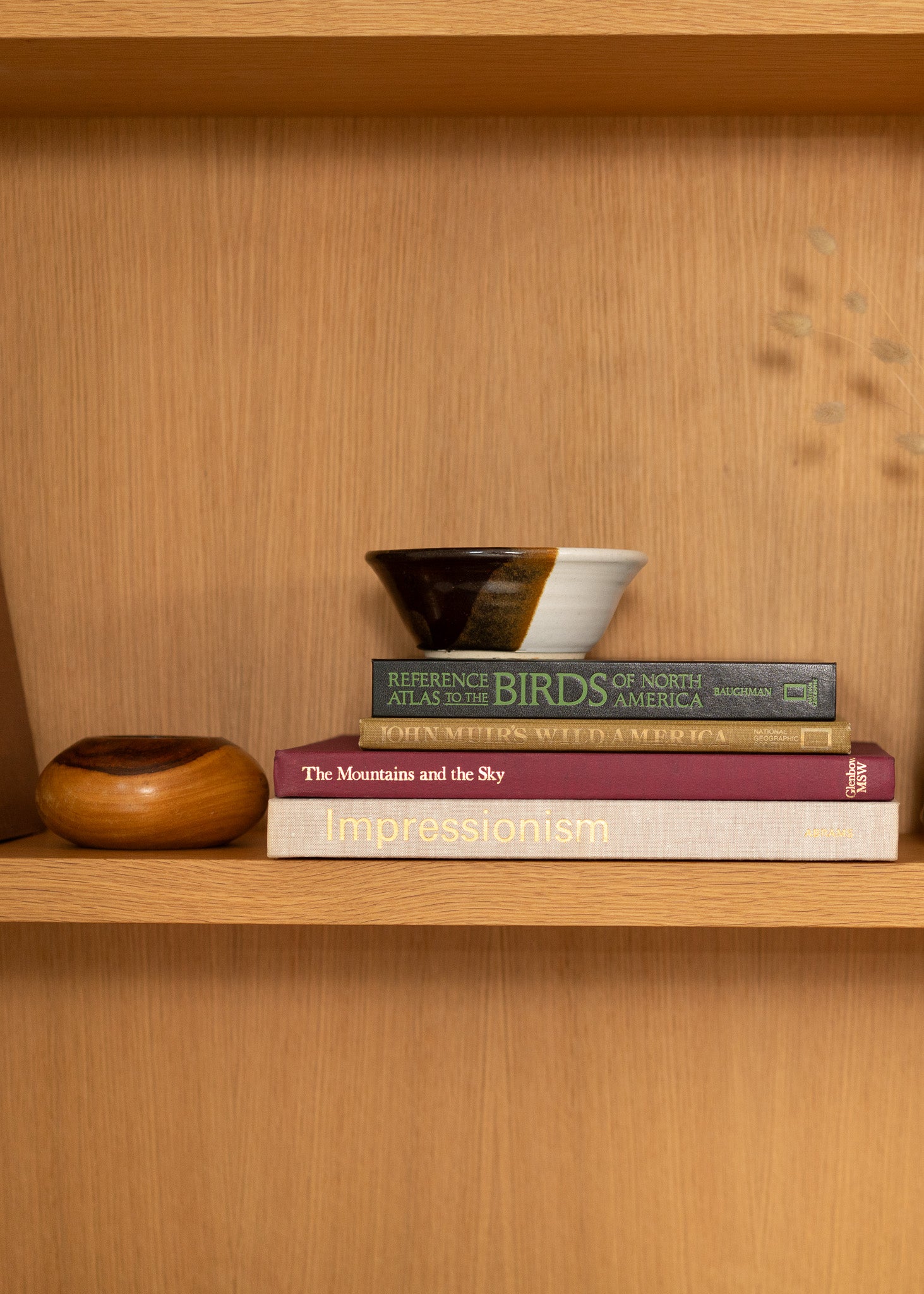 Stack of vintage books on a wooden shelf with decorative bowls.