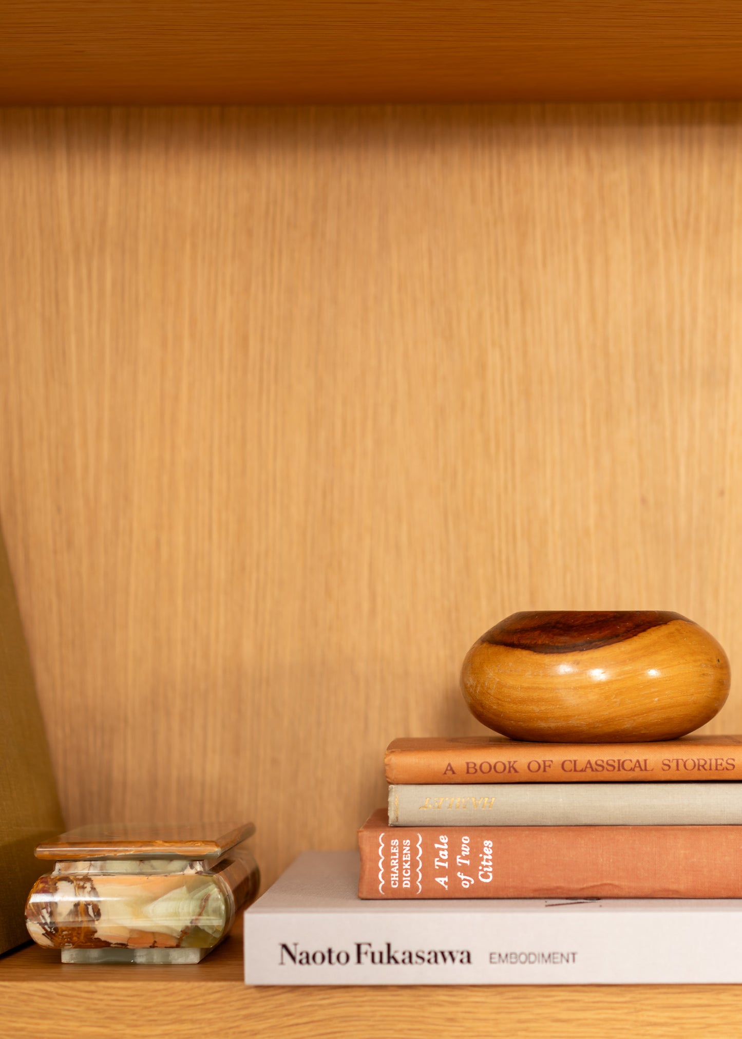 Stack of books with a vintage wooden bowl on a wooden shelf
