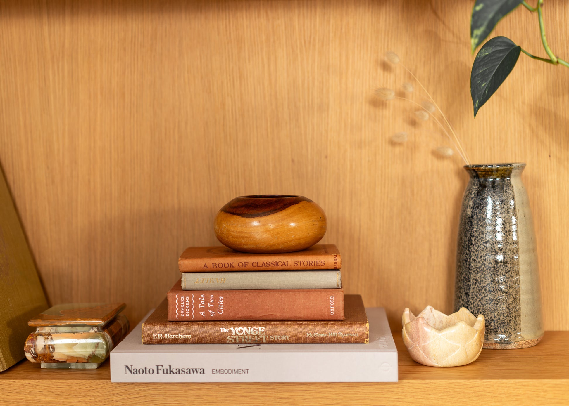 Stack of books on a wooden shelf with decorative items