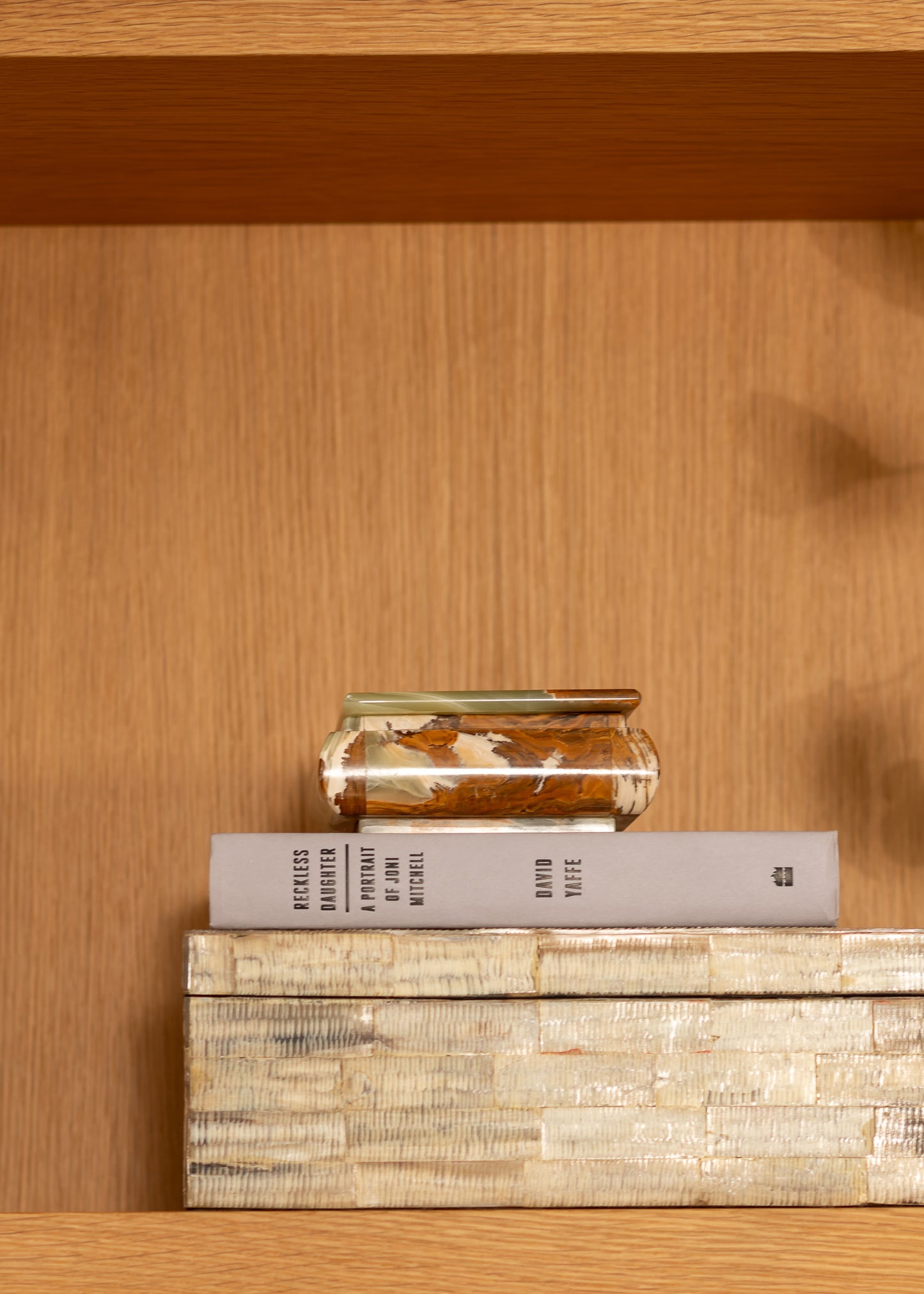 Stack of books and a vintage onyx box on a wooden shelf