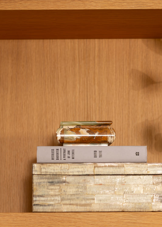 Stack of books and a vintage onyx box on a wooden shelf