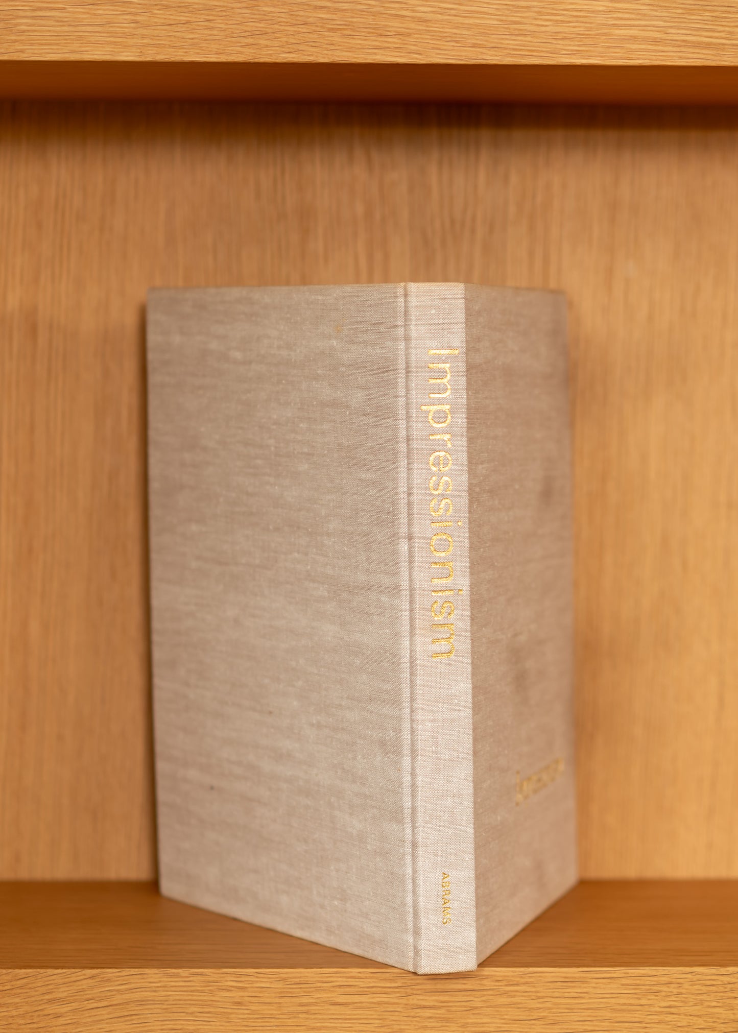 vintage book titled 'Impressionism' on a wooden shelf
