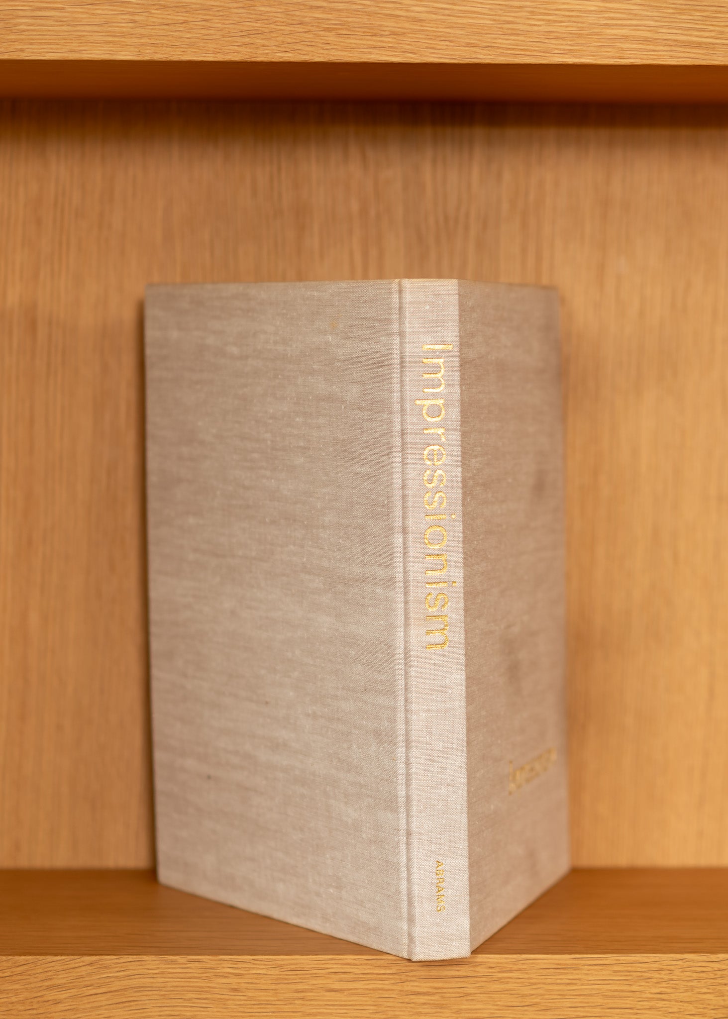 vintage book titled 'Impressionism' on a wooden shelf