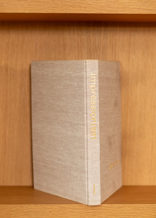 vintage book titled 'Impressionism' on a wooden shelf
