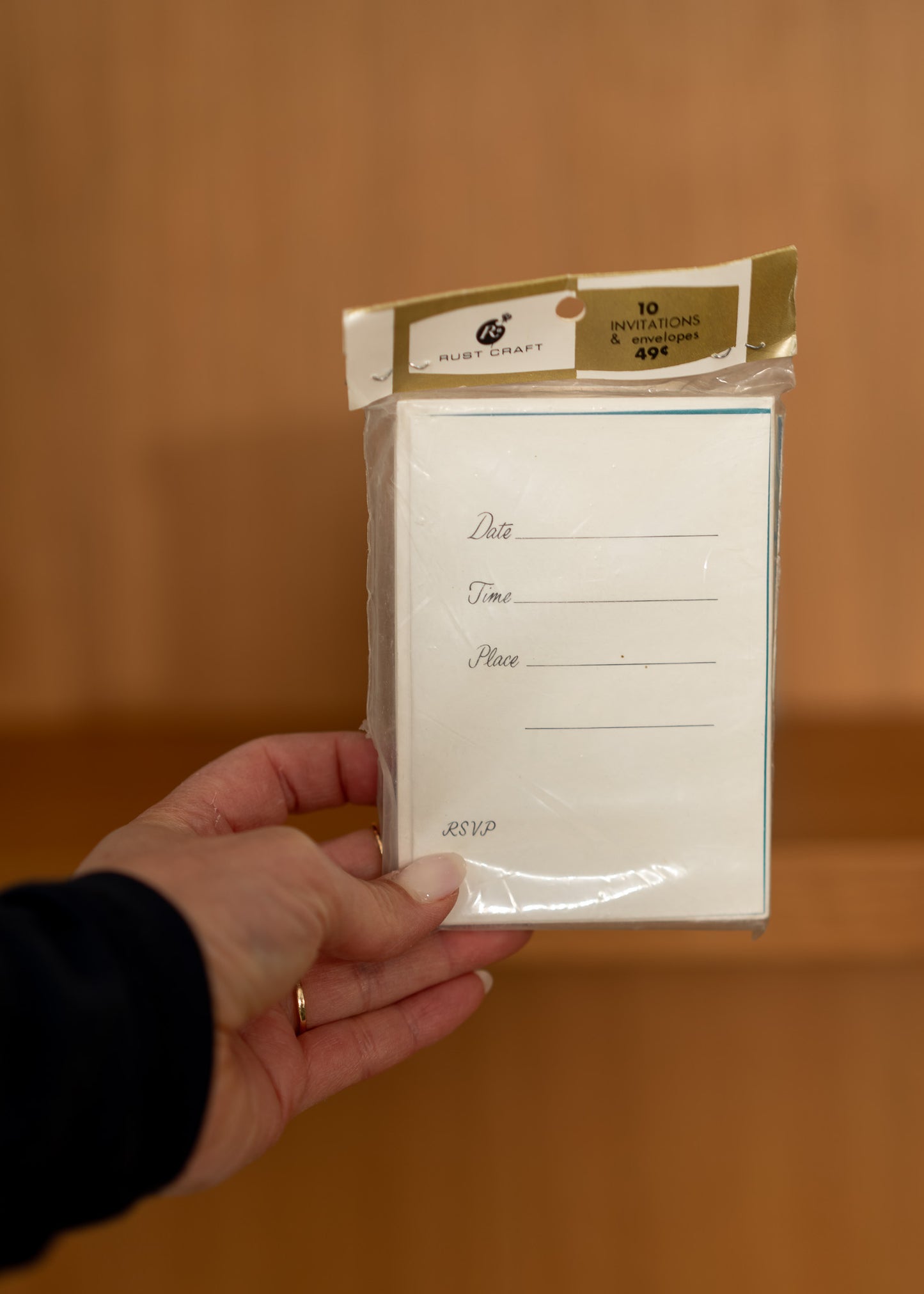 Hand holding a package of vintage stationery items with a plain background