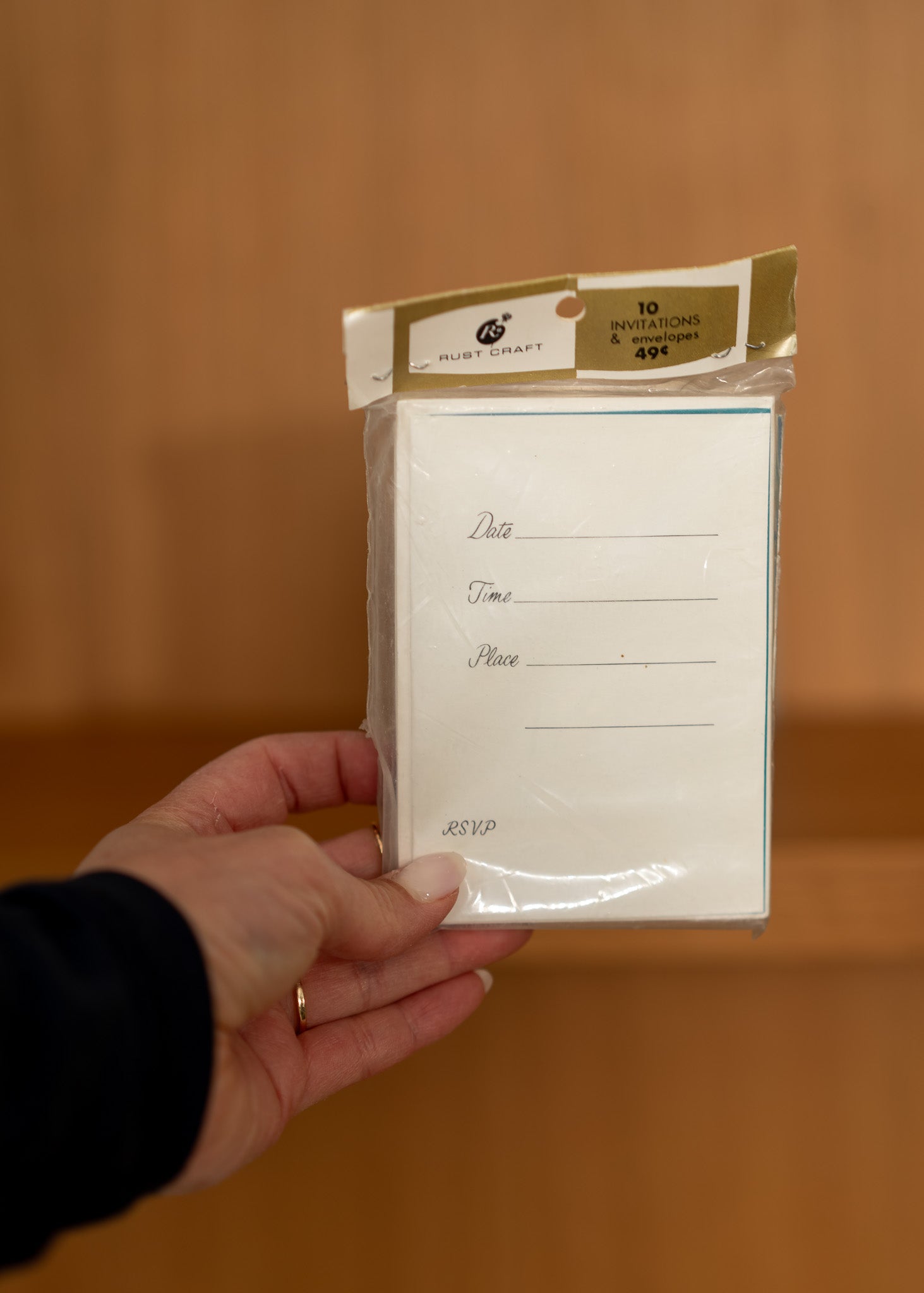 Hand holding a package of vintage stationery items with a plain background