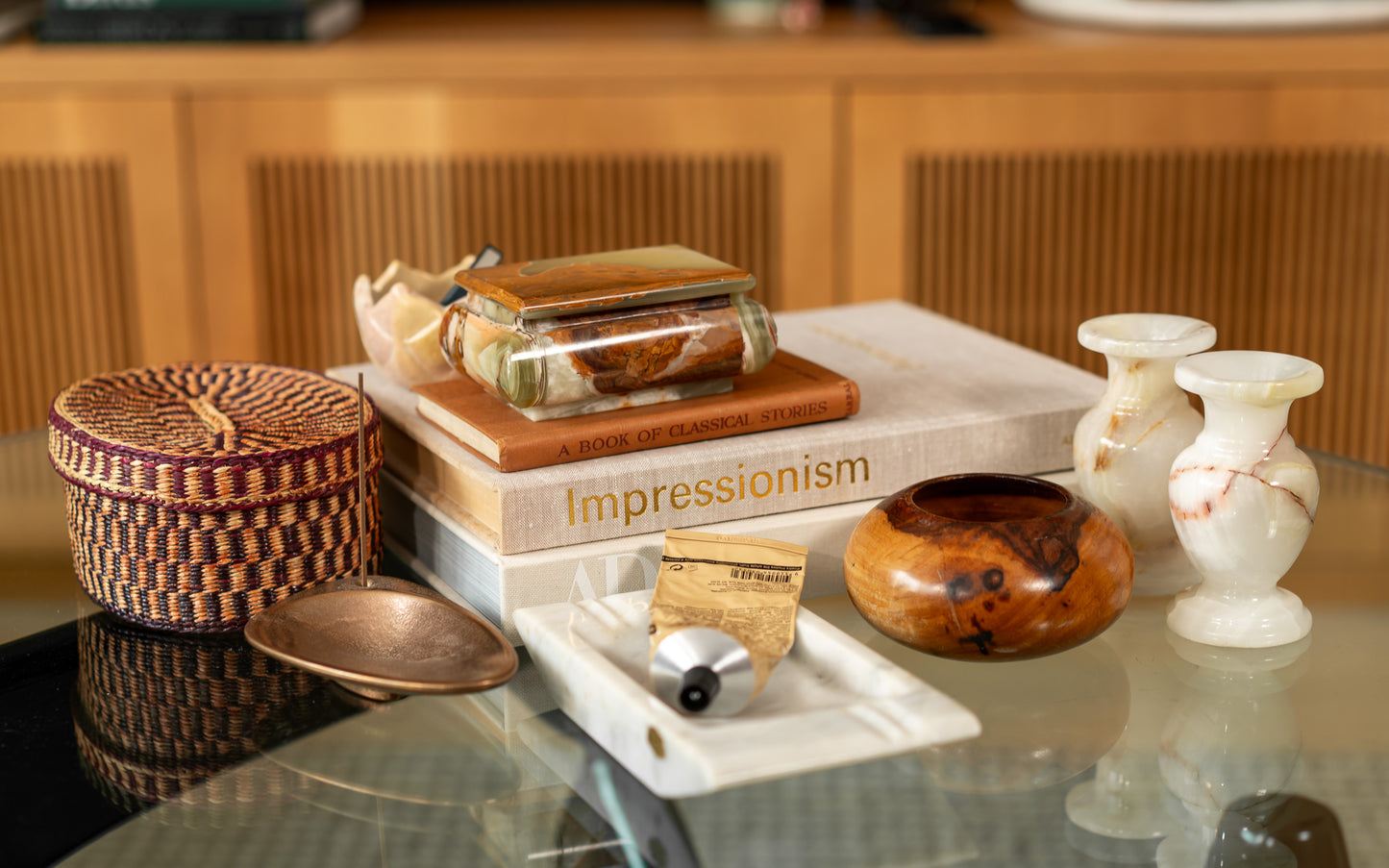 Decorative items including a woven basket, books, and vintage onyx candle holders on a reflective surface.
