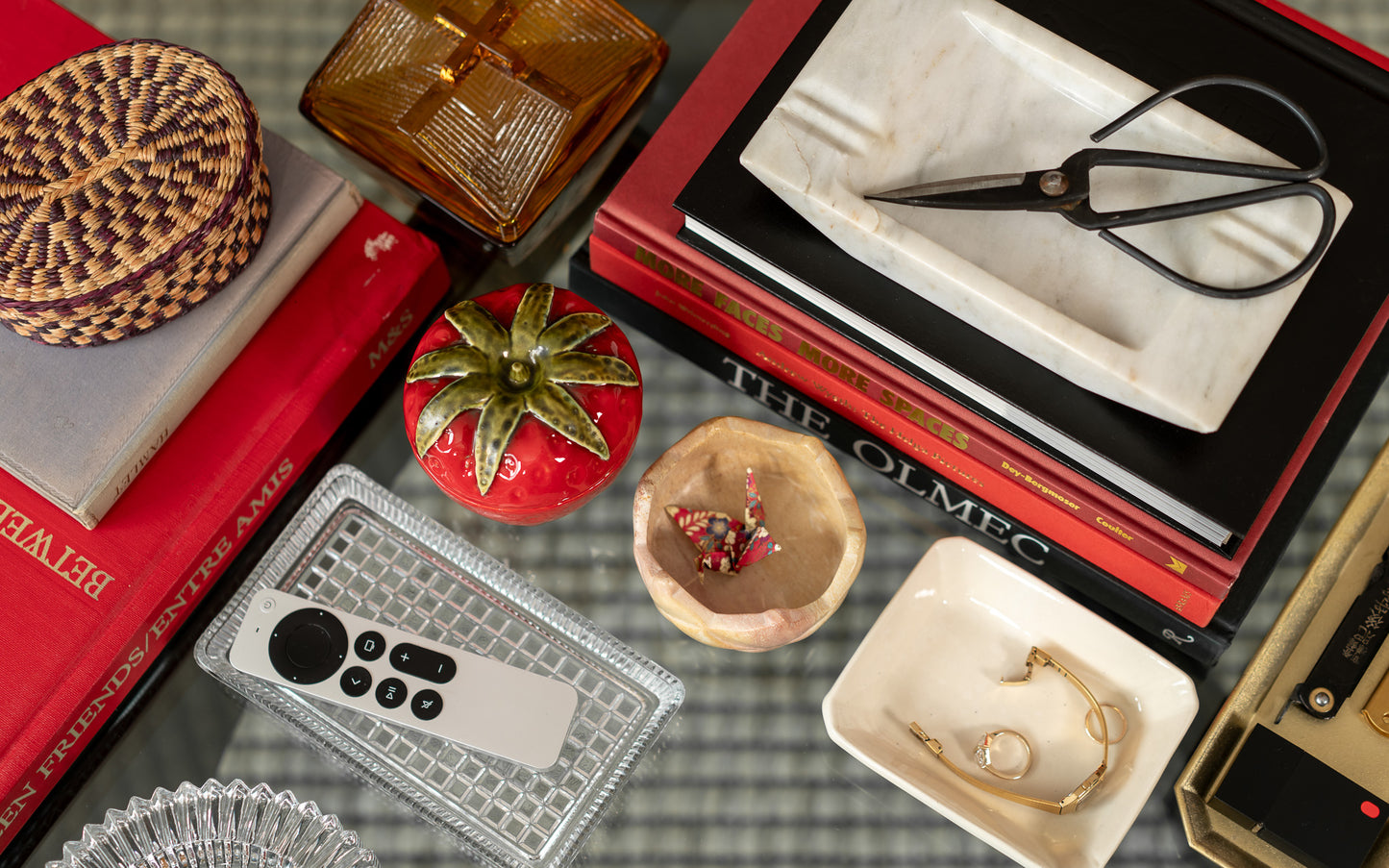 Collection of decorative items including vintage books, a plant, and small containers on a textured surface.