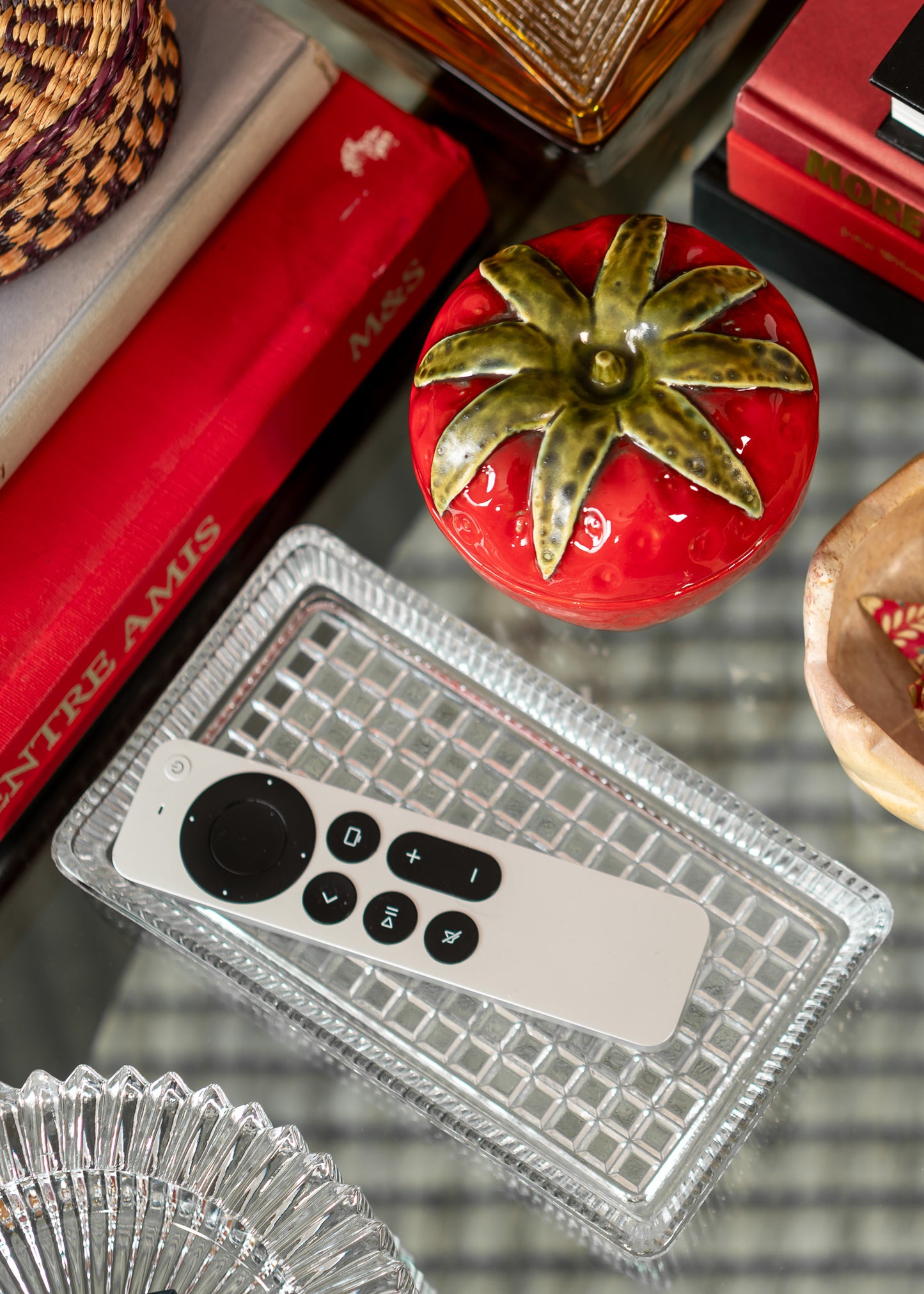Clear vintage glass tray on a glass surface with decorative items.