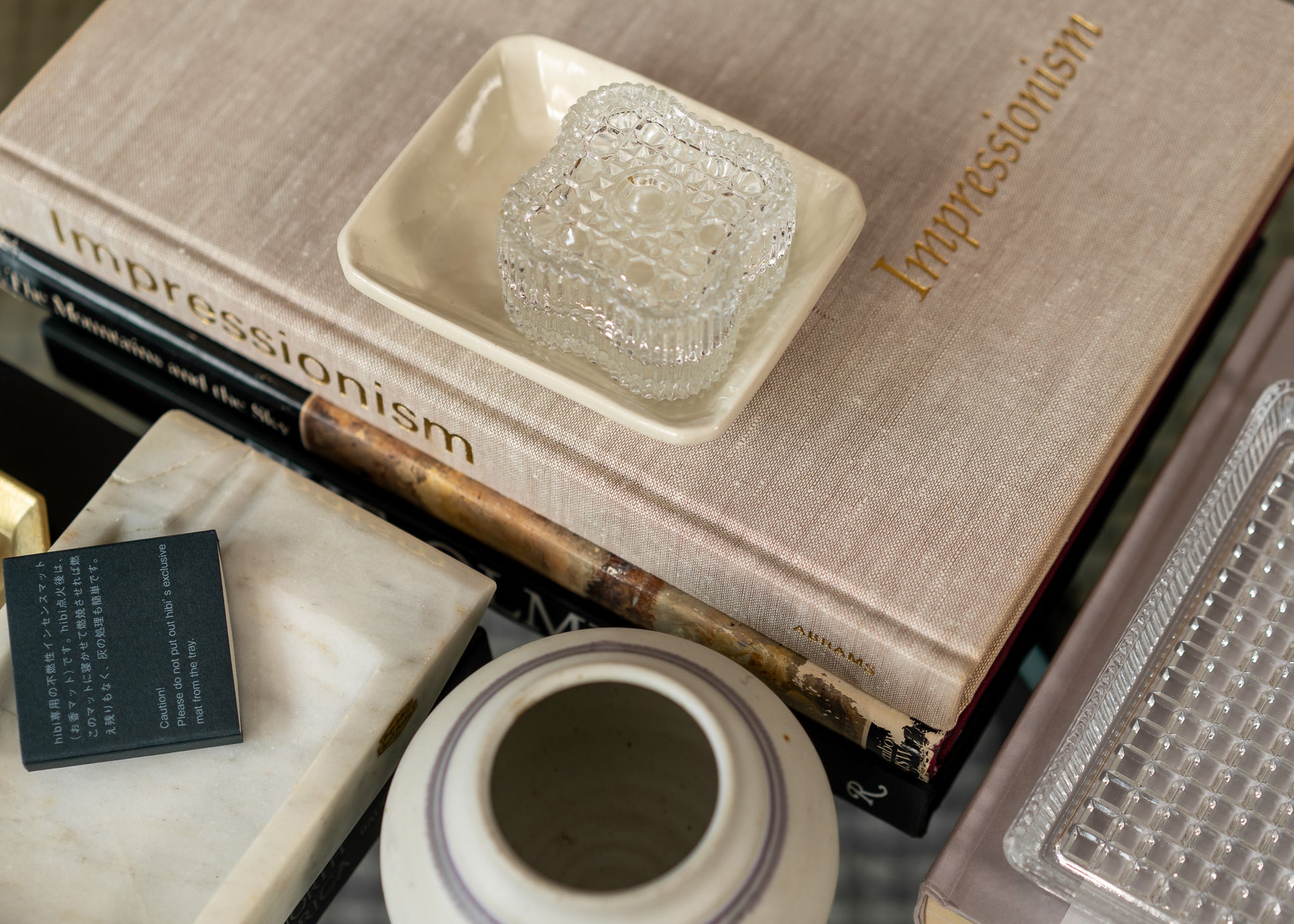 Decorative setting with vintage books, a ceramic bowl, and a vase on a textured surface.