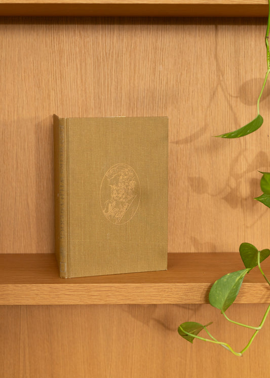 vintage brown book with embossed gold design on a wooden shelf