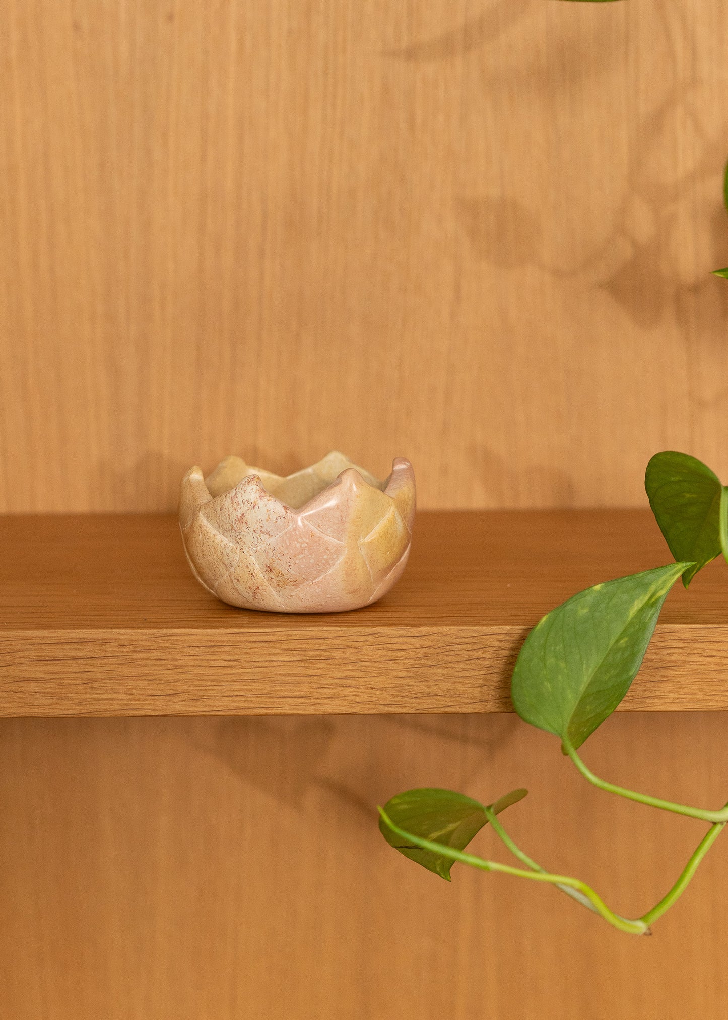 Small vintage stone bowl on a wooden shelf with a wooden wall background
