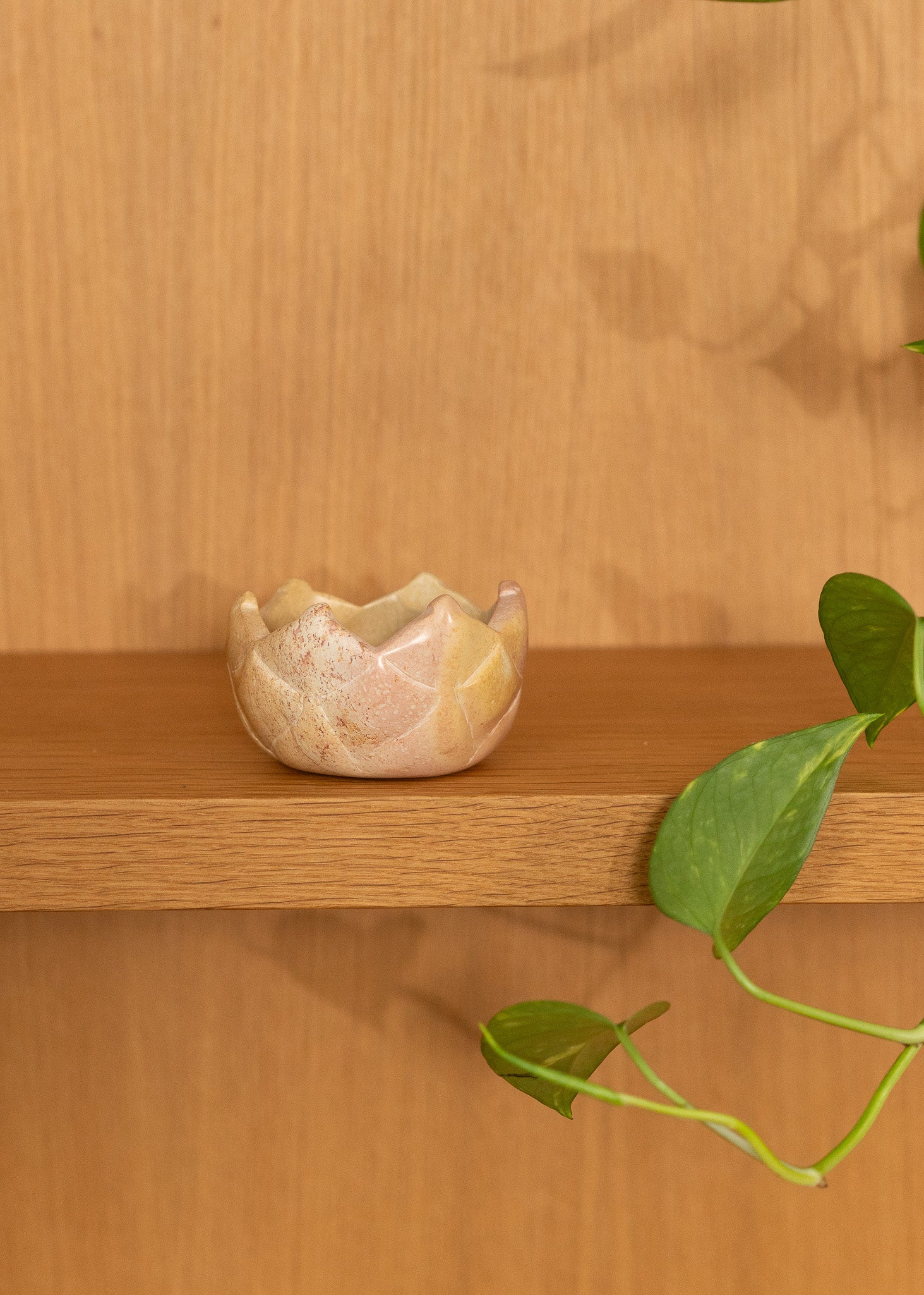 Small vintage stone bowl on a wooden shelf with a wooden wall background