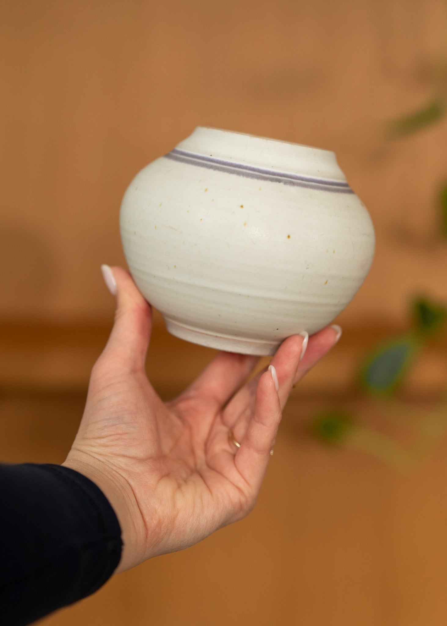 Hand holding a small vintage ceramic bowl with a blurred background