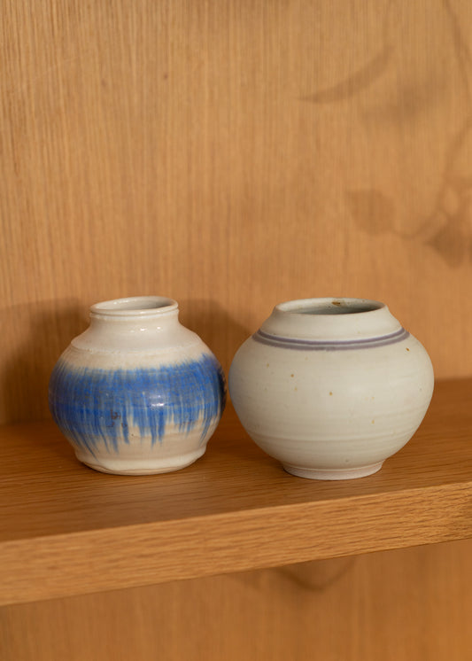 Two vintage ceramic jars on a wooden shelf with a wooden background