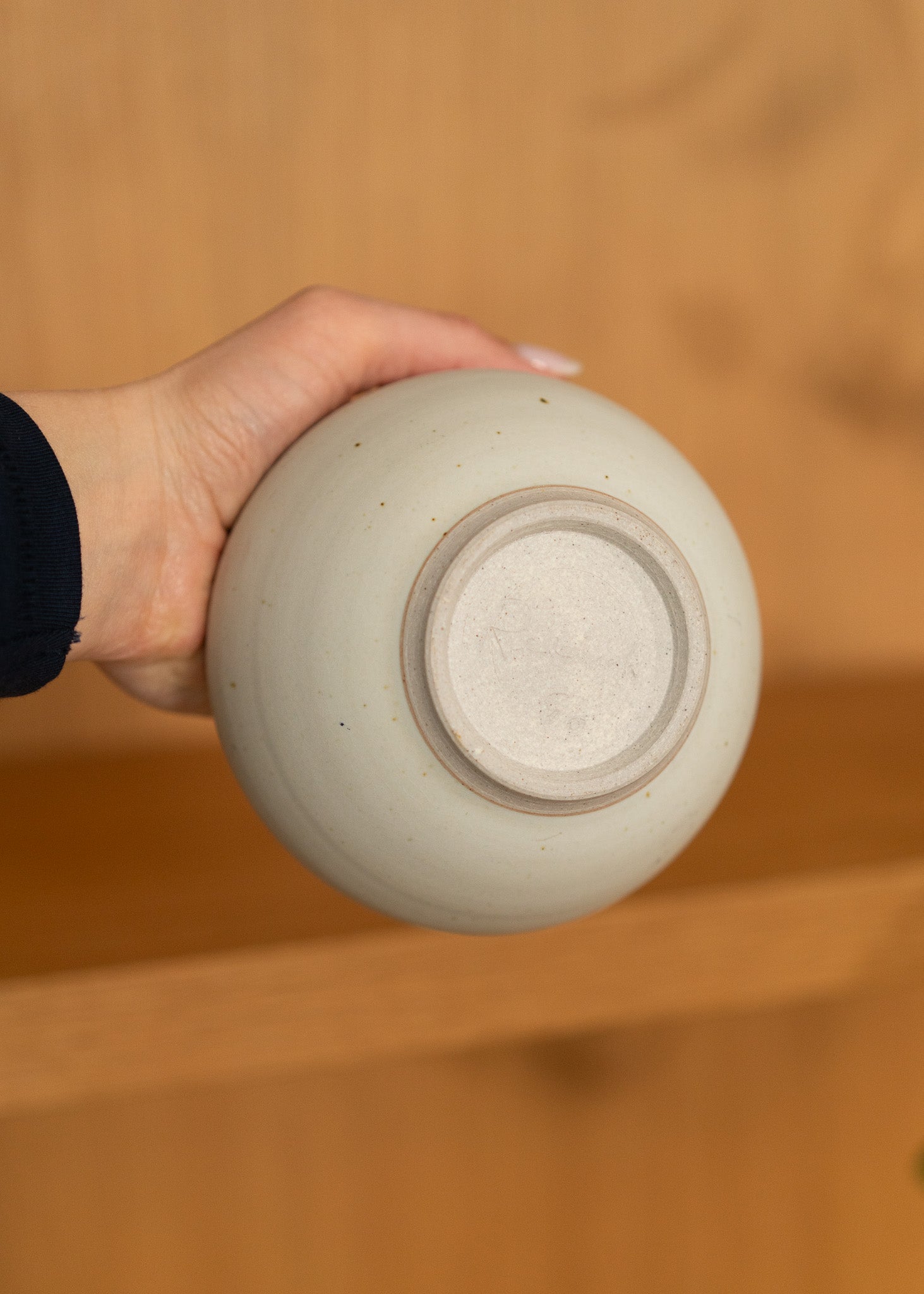 Hand holding a vintage ceramic bowl against a wooden background