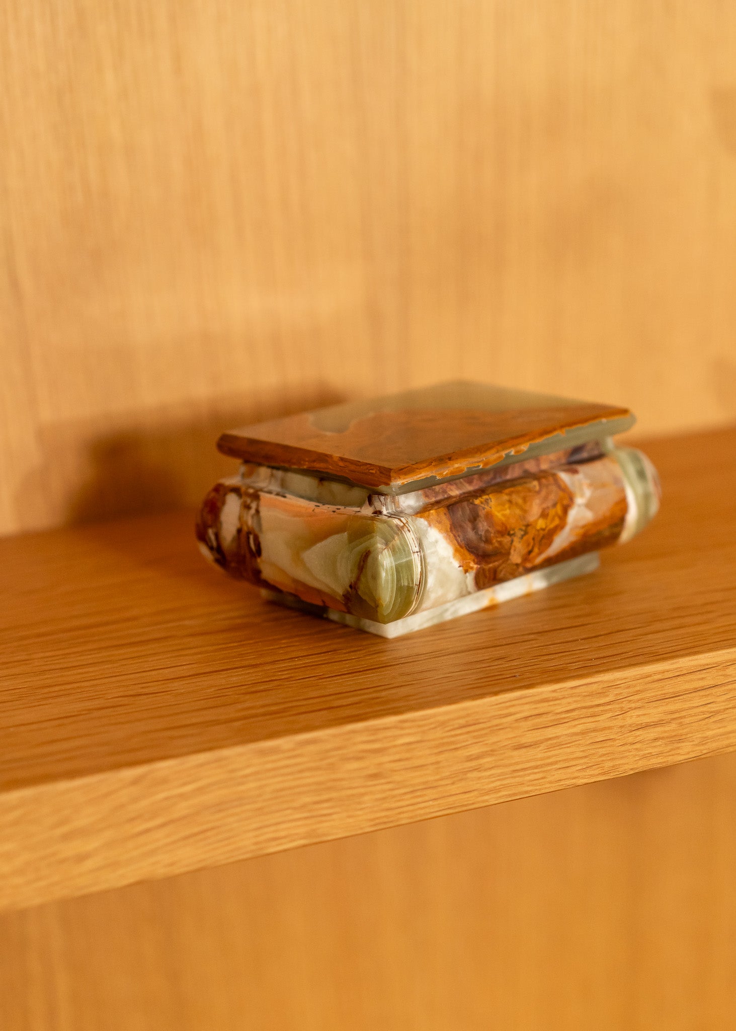 Decorative vintage onyx box on a wooden shelf with a warm wooden background