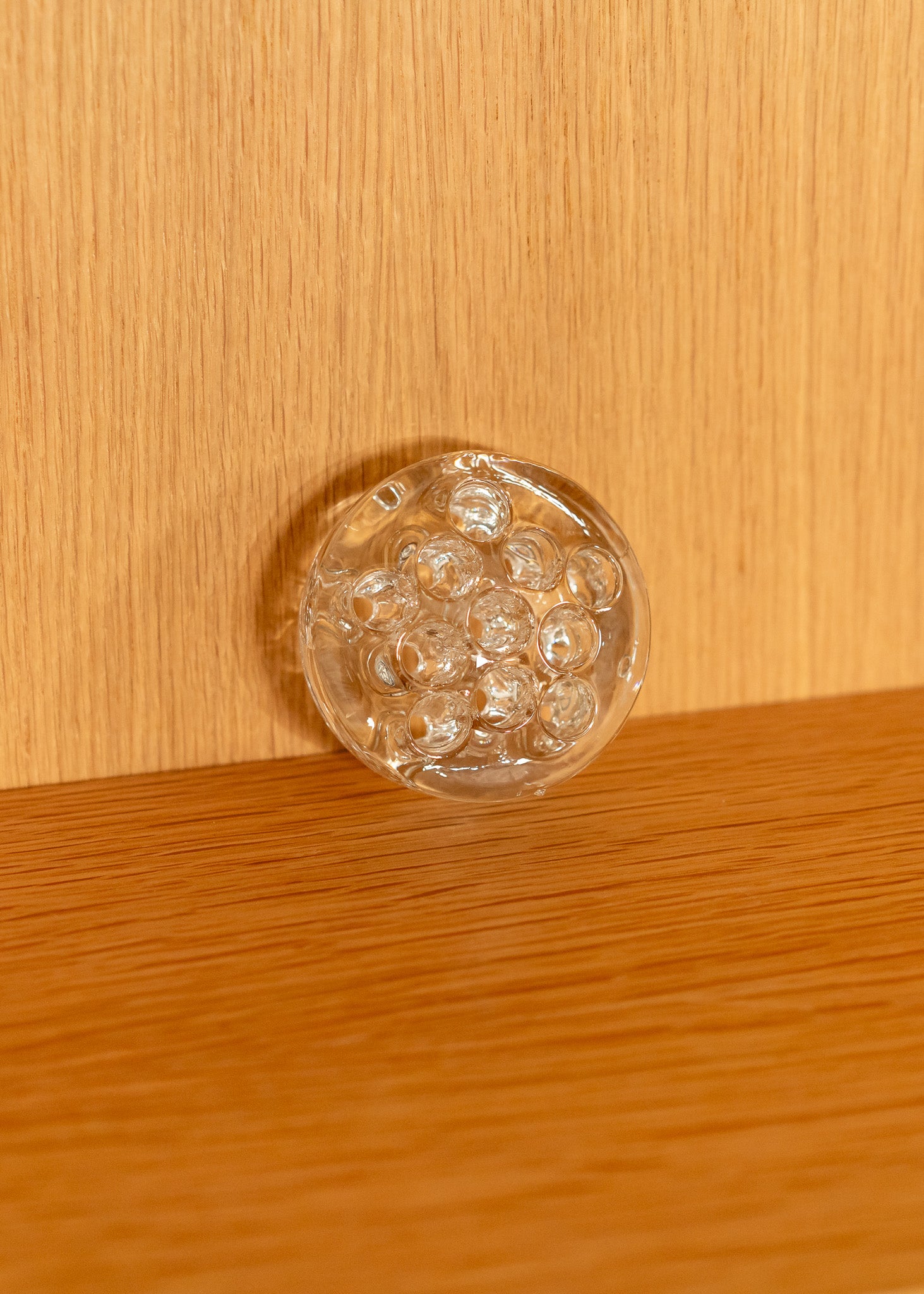 a vintage round, clear glass flower frog against a wooden background