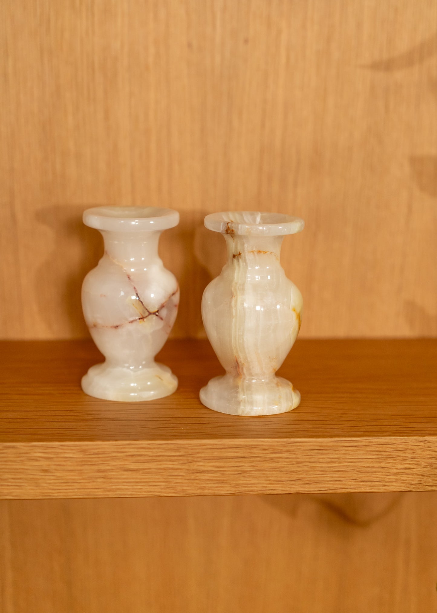 Two vintage onyx candle holders on a wooden shelf with a wooden background