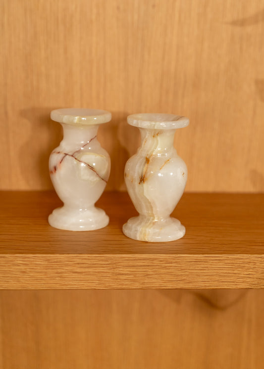 Two vintage onyx candle holders on a wooden shelf with a wooden background