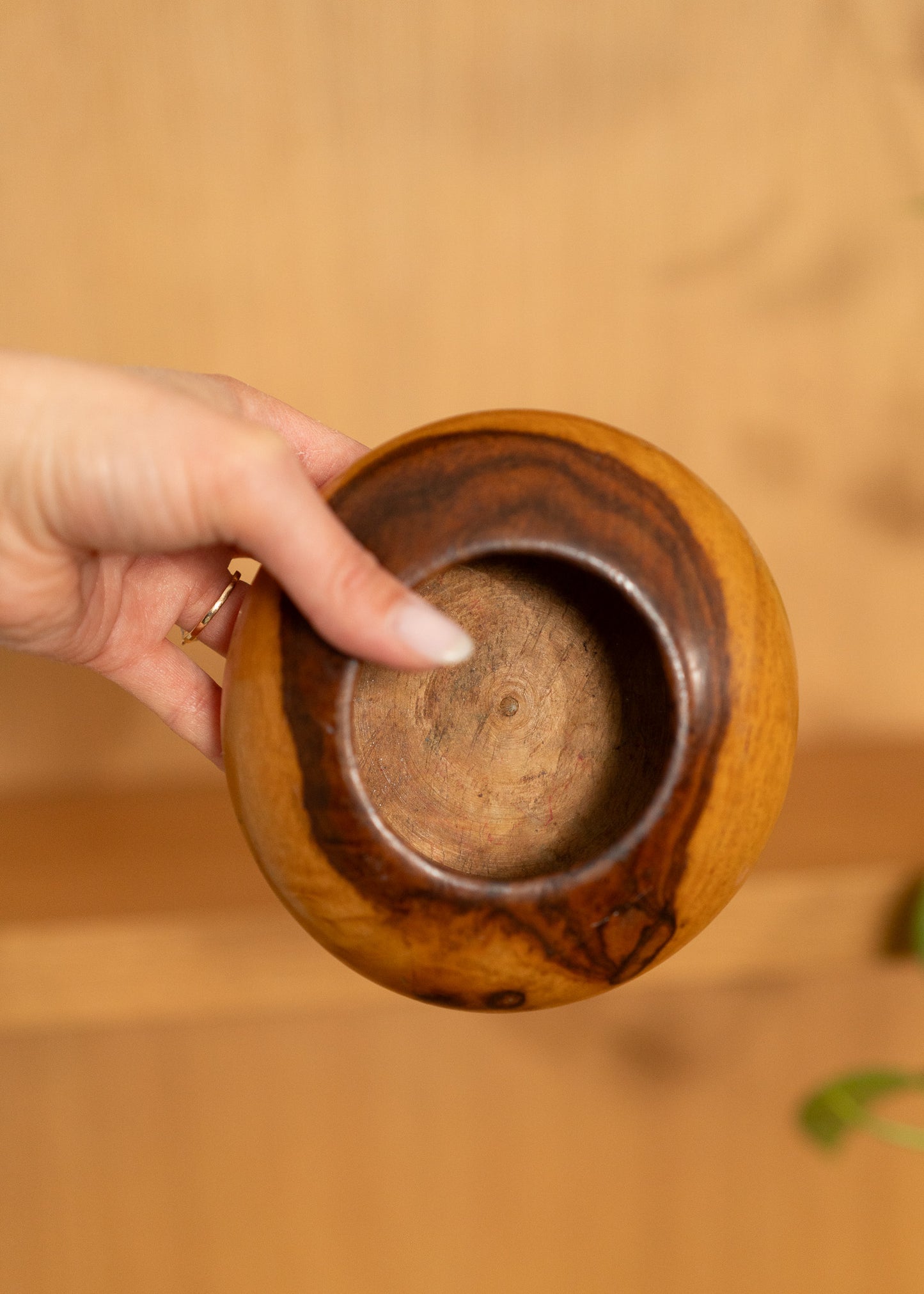 vintage wooden bowl held by a hand with a blurred background