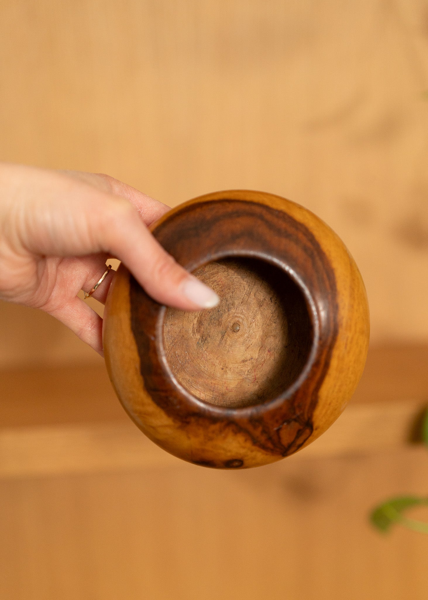 vintage wooden bowl held by a hand with a blurred background