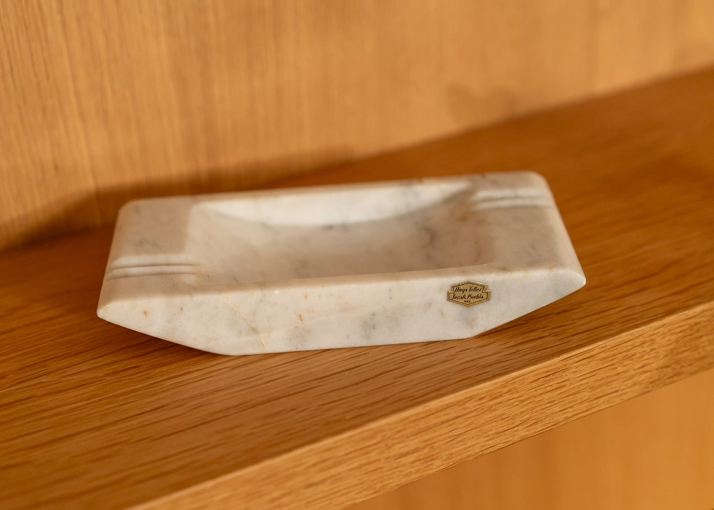 Onyx ashtray with a brand logo on a wooden surface