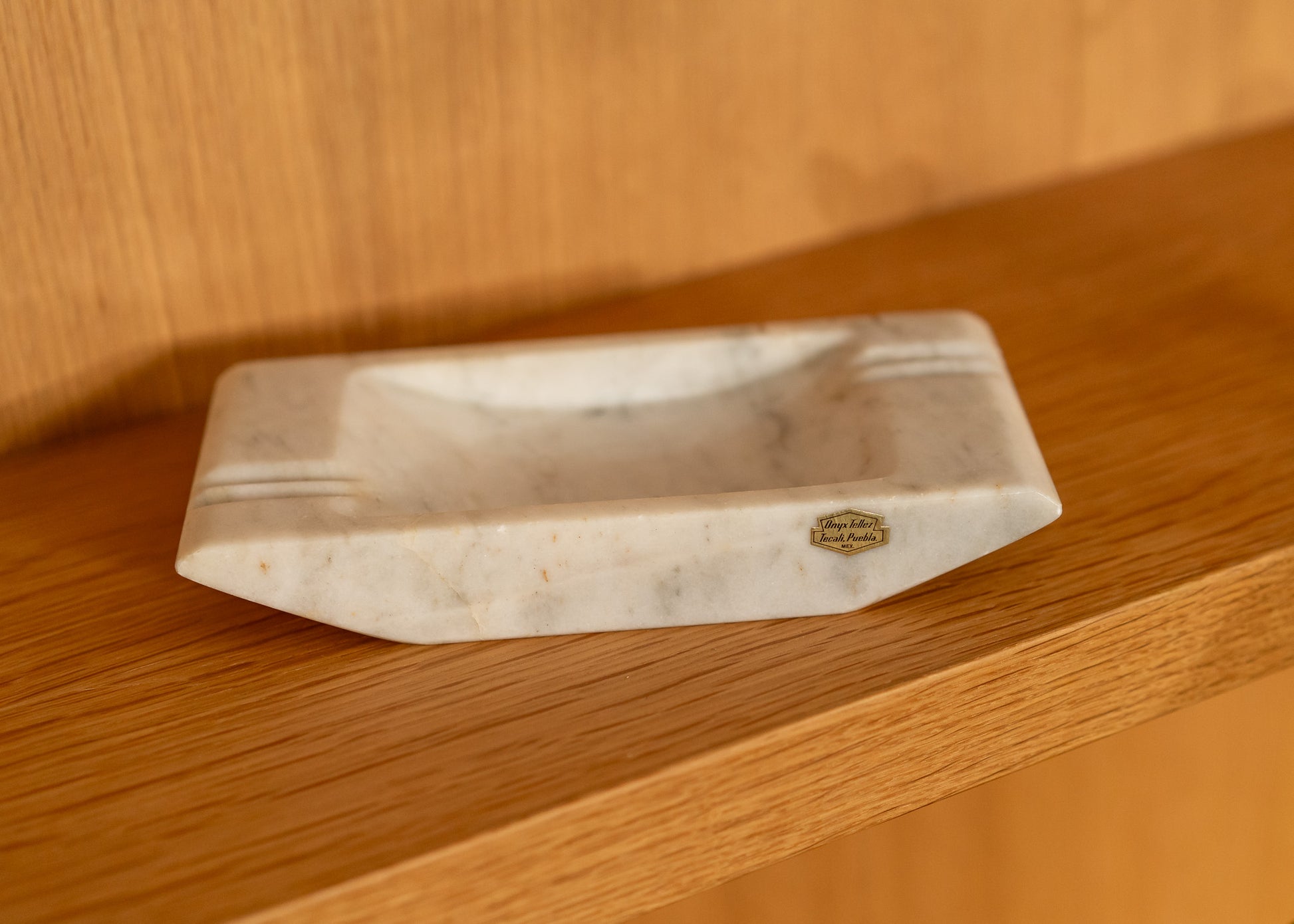 Onyx ashtray with a brand logo on a wooden surface