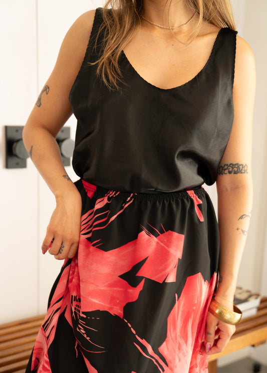 Person wearing a vintage black sleeveless top and pink and black floral skirt indoors.