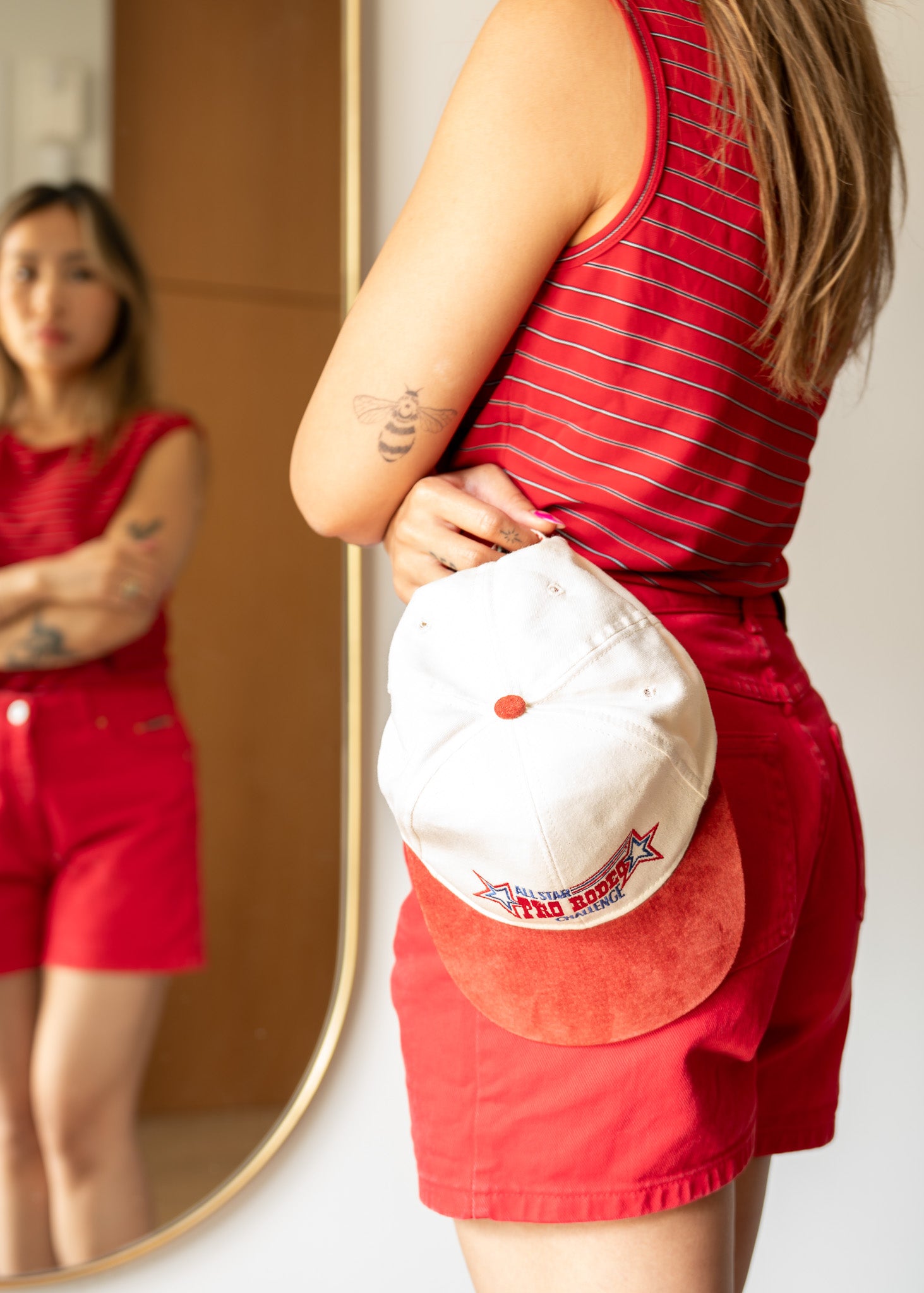 Person wearing a red outfit with a red suede and cotton embroidered cap, standing in front of a mirror.