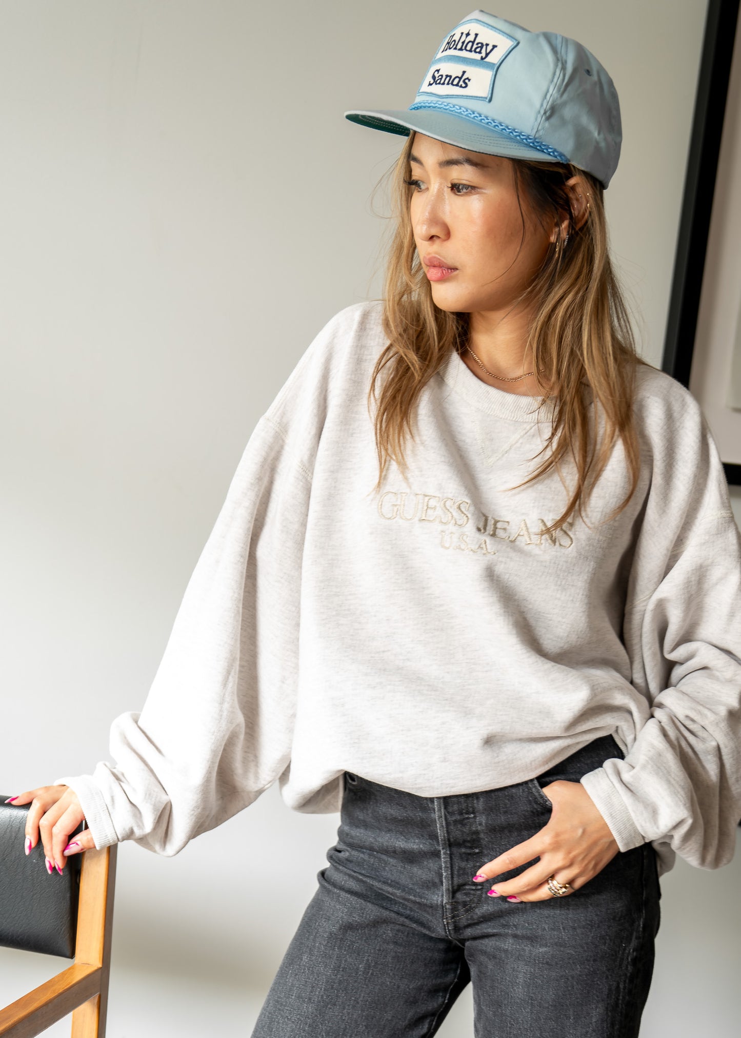 Person wearing an oversized light gray sweatshirt and blue cap indoors