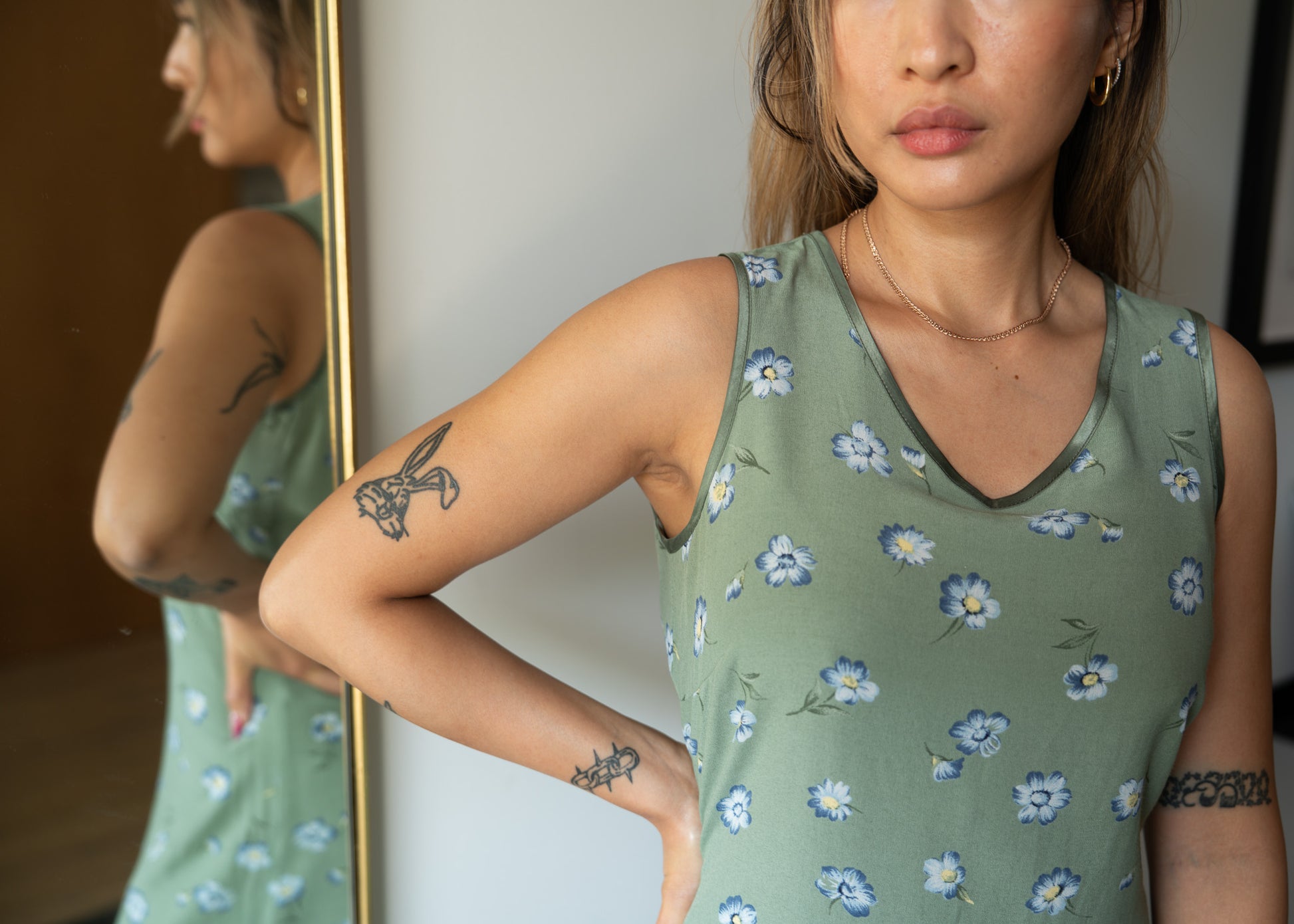 Woman wearing a green floral sleeveless dress in front of a mirror.