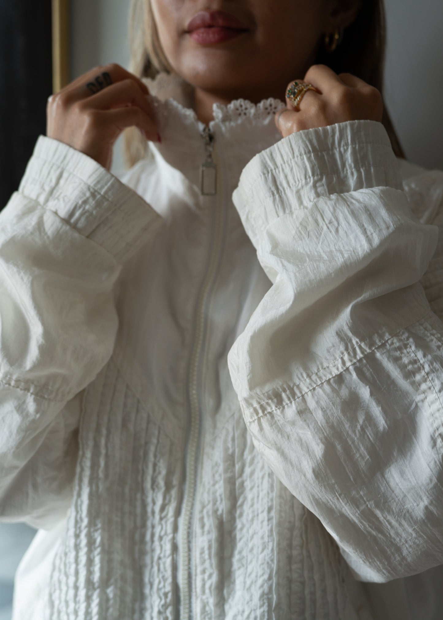 Close-up of a person wearing a floral and textured white jacket with a focus on the collar and sleeves.