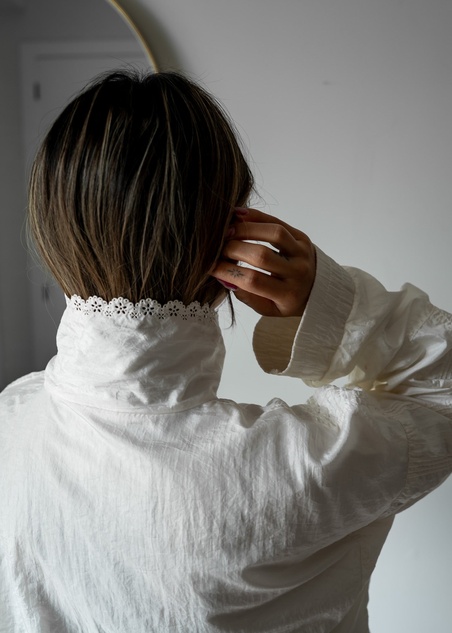Person wearing a white jacket with lace collar against a plain background