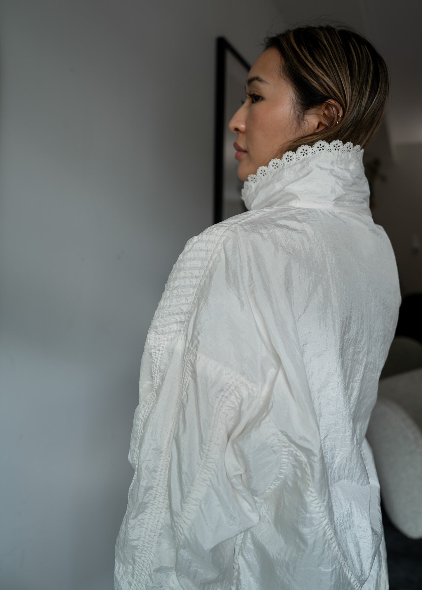 Woman wearing a white lace-trimmed jacket against a neutral background
