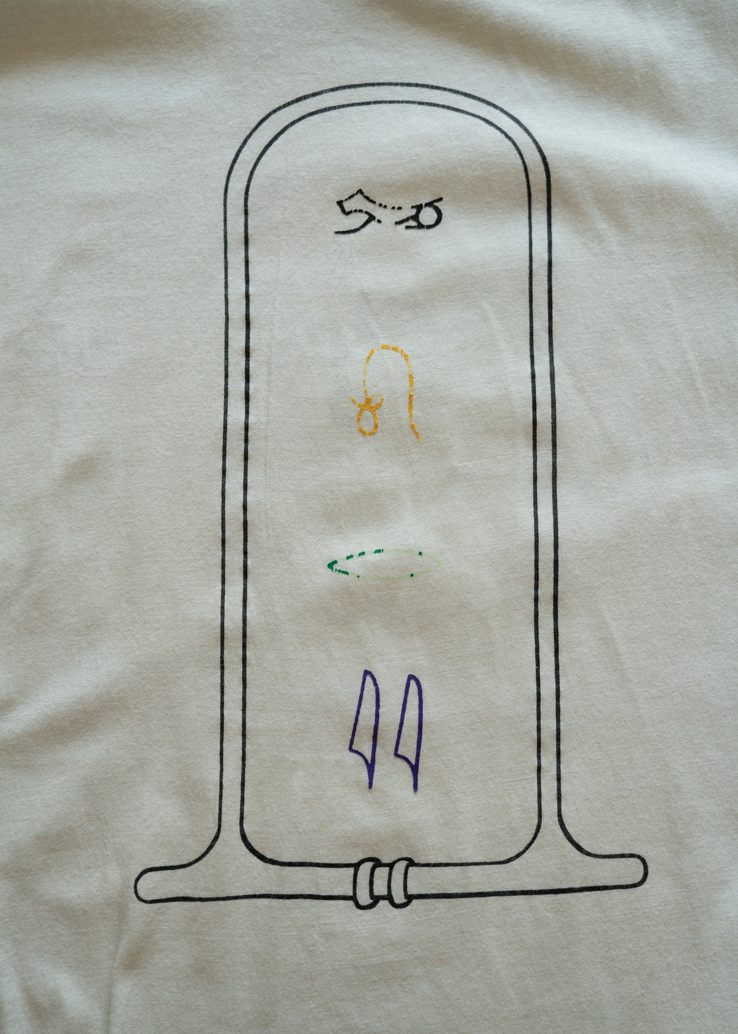 graphic design of Egyptian hieroglyphs on a white fabric background