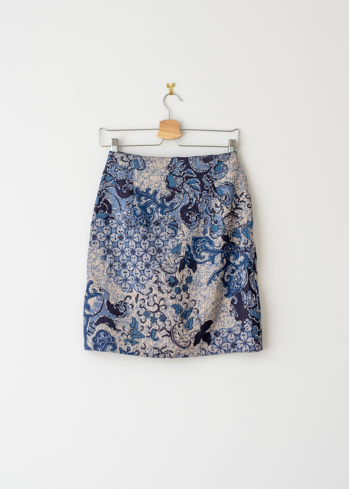 knee-length blue floral pattern vintage pencil skirt on a hanger against a white background